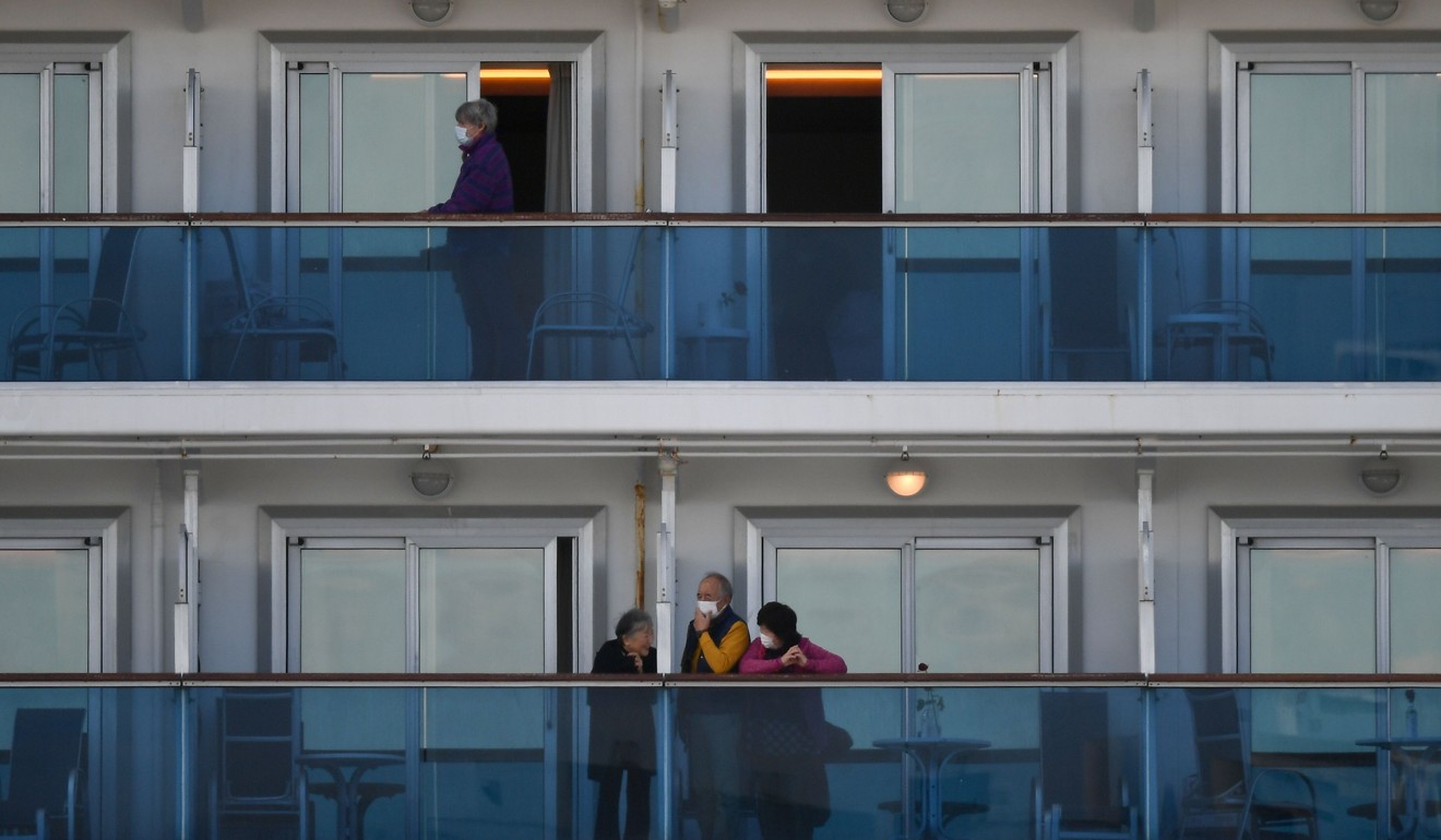 Passengers talk to each other from the balconies of their cabins on board the cruise ship. Photo: AFP