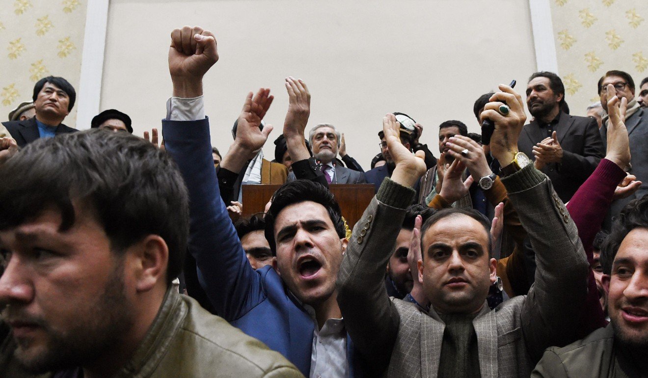People cheer as Afghan presidential election opposition candidate Abdullah Abdullah, behind the podium, speaks to the media after the announcement of the final presidential election results. Photo: AFP