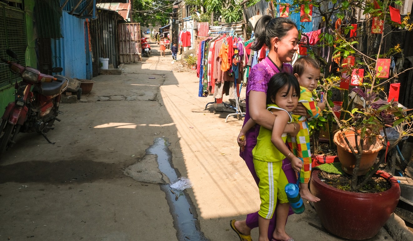 A Vietnamese woman carries her two children to their home in Chbar Ampov which has a cherry blossom tree outside to mark the Lunar New Year. Photo: Peter Ford