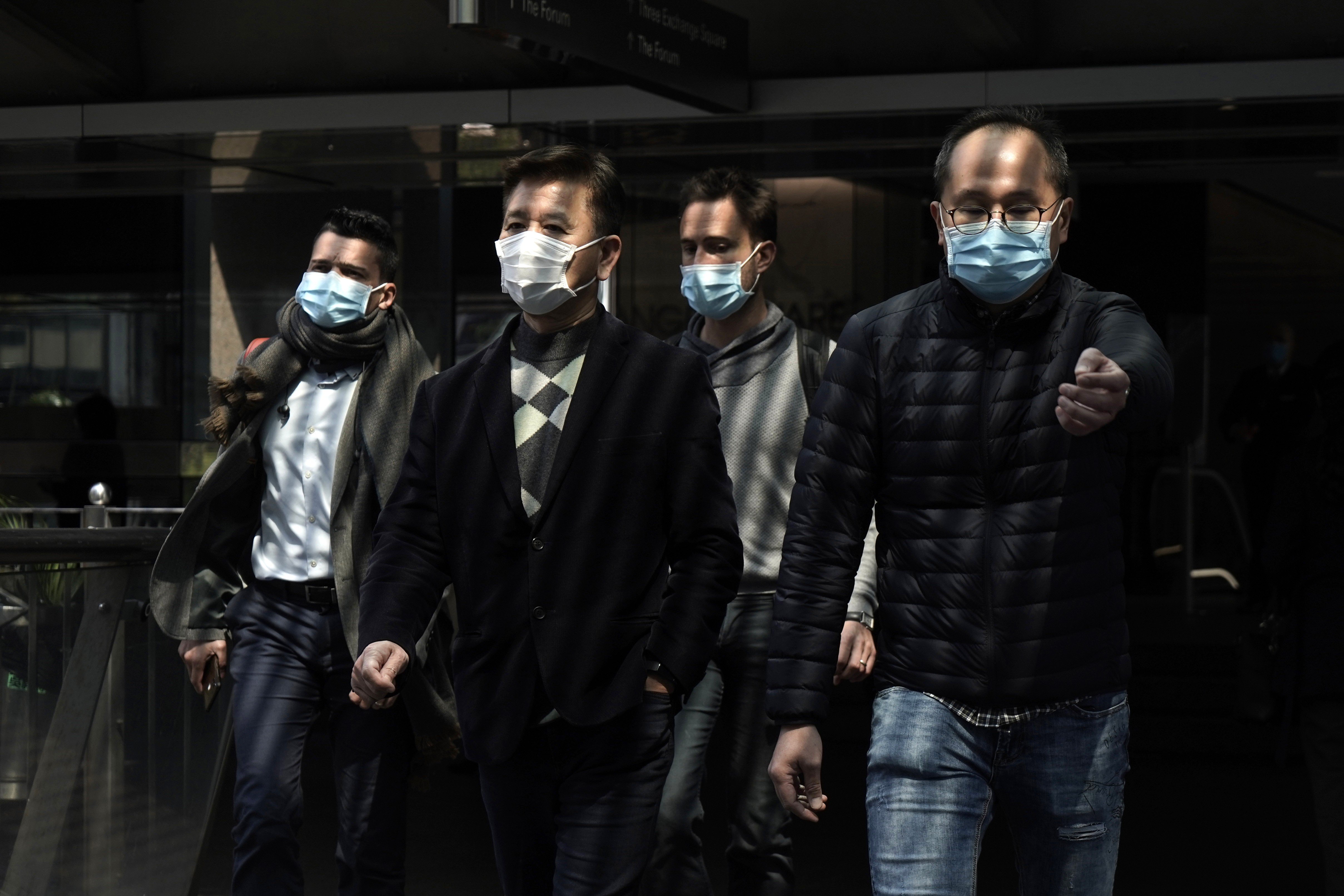 People wearing masks walk through the Hong Kong business district of Central on February 19. Given their wealth, resources and organisational heft, conglomerates in Hong Kong ought to be doing much more to contribute to bettering the coronavirus situation. Photo: AP