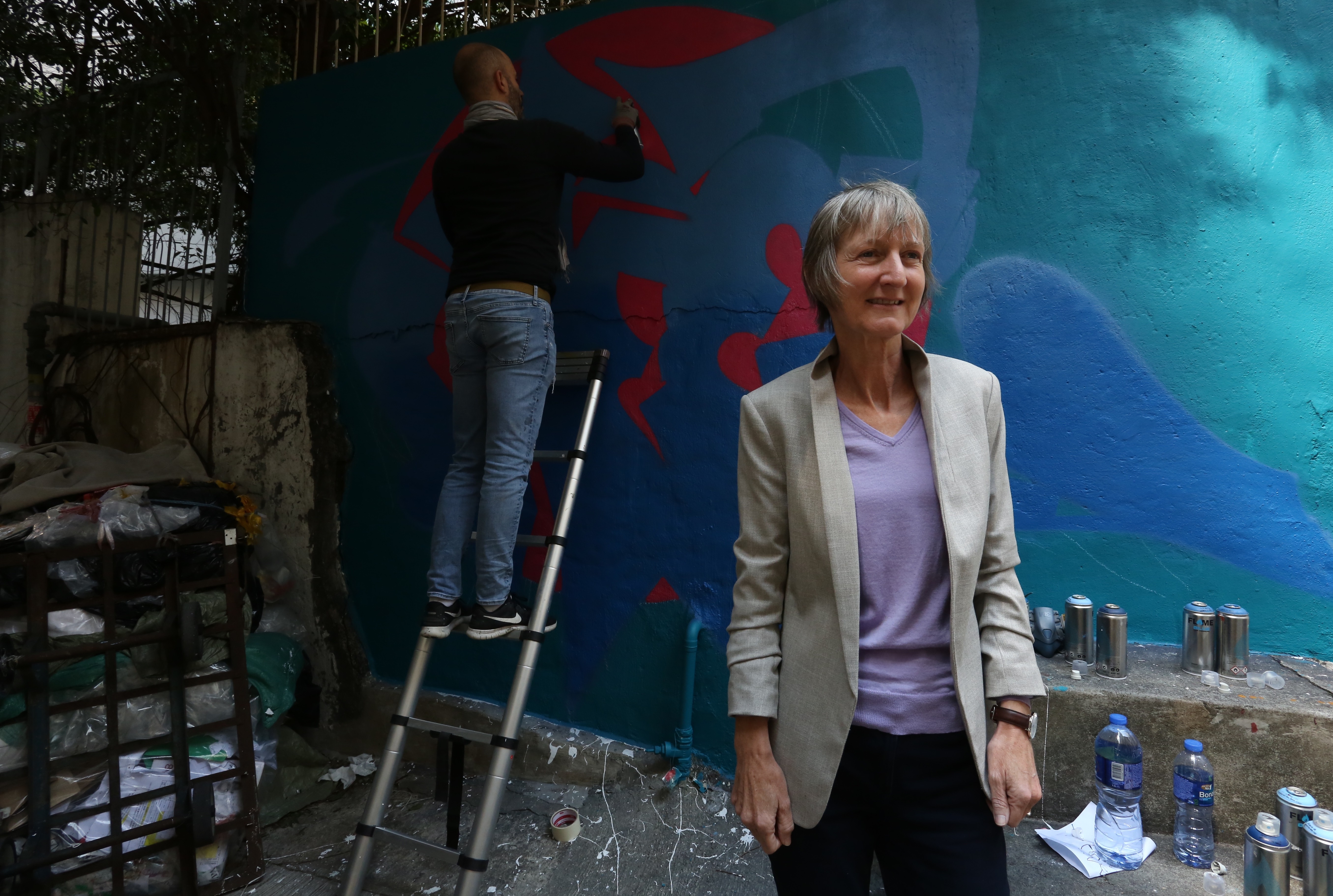 Ann Pearce pose in front of mural paint done by Miguel, during the Week Wall on Hollywood road, Hong Kong. SCMP / Jonathan Wong [FEATURES 2020]