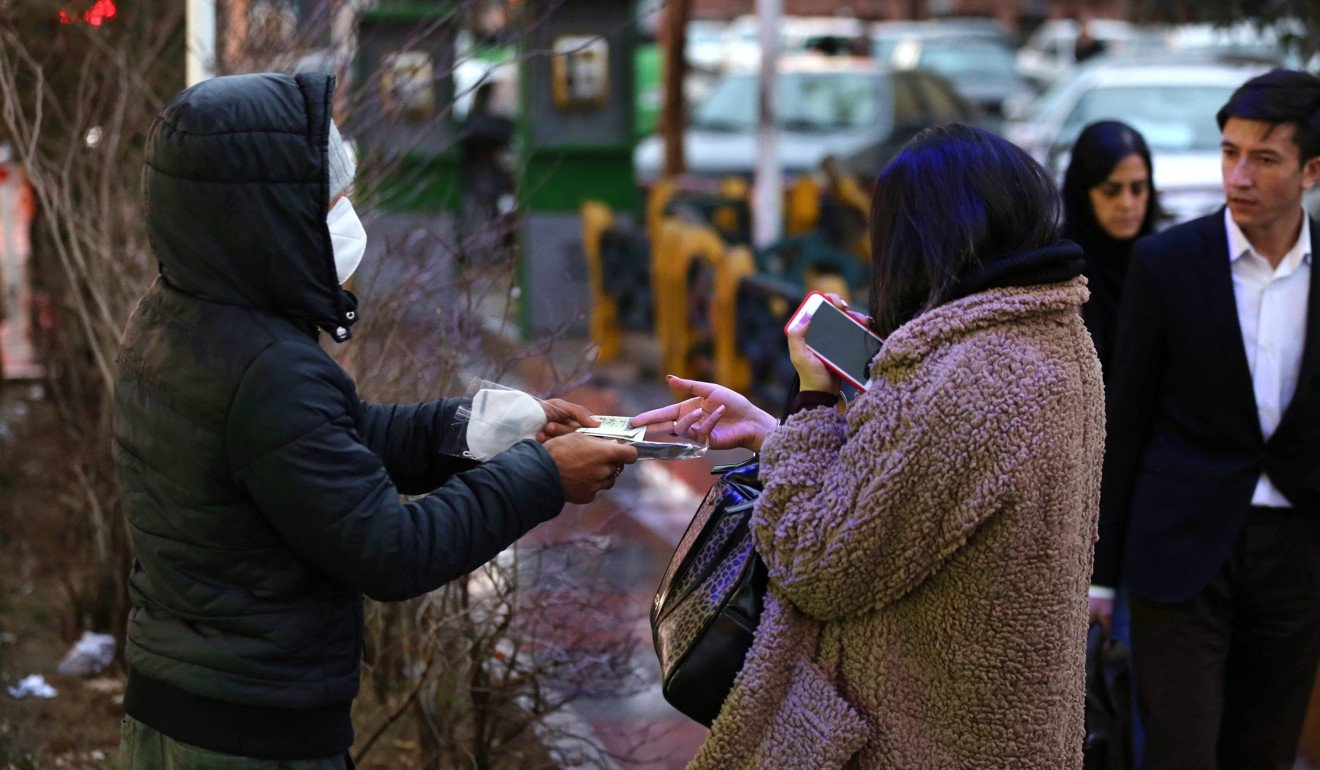 A woman buys a face mask from a street vendor in Tehran on Thursday. Iran reported its first cases of the virus on February 13. Photo: AFP