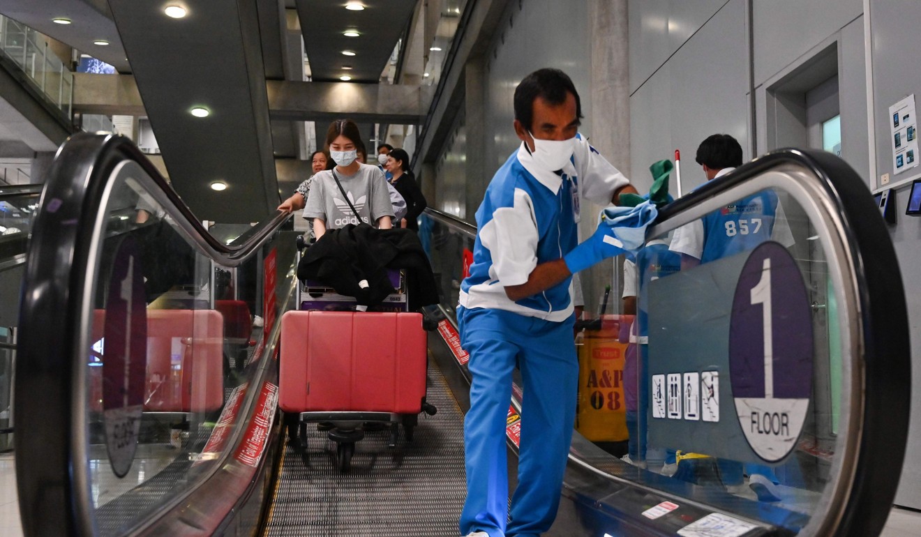 Staff disinfect handrails at Suvarnabhumi Airport in Bangkok. Photo: AFP
