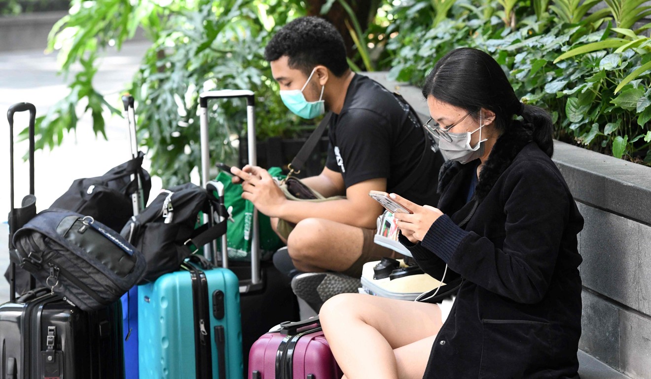Travellers wearing protective face masks look at their phones at Singapore’s Changi Airport on Thursday. Photo: AFP