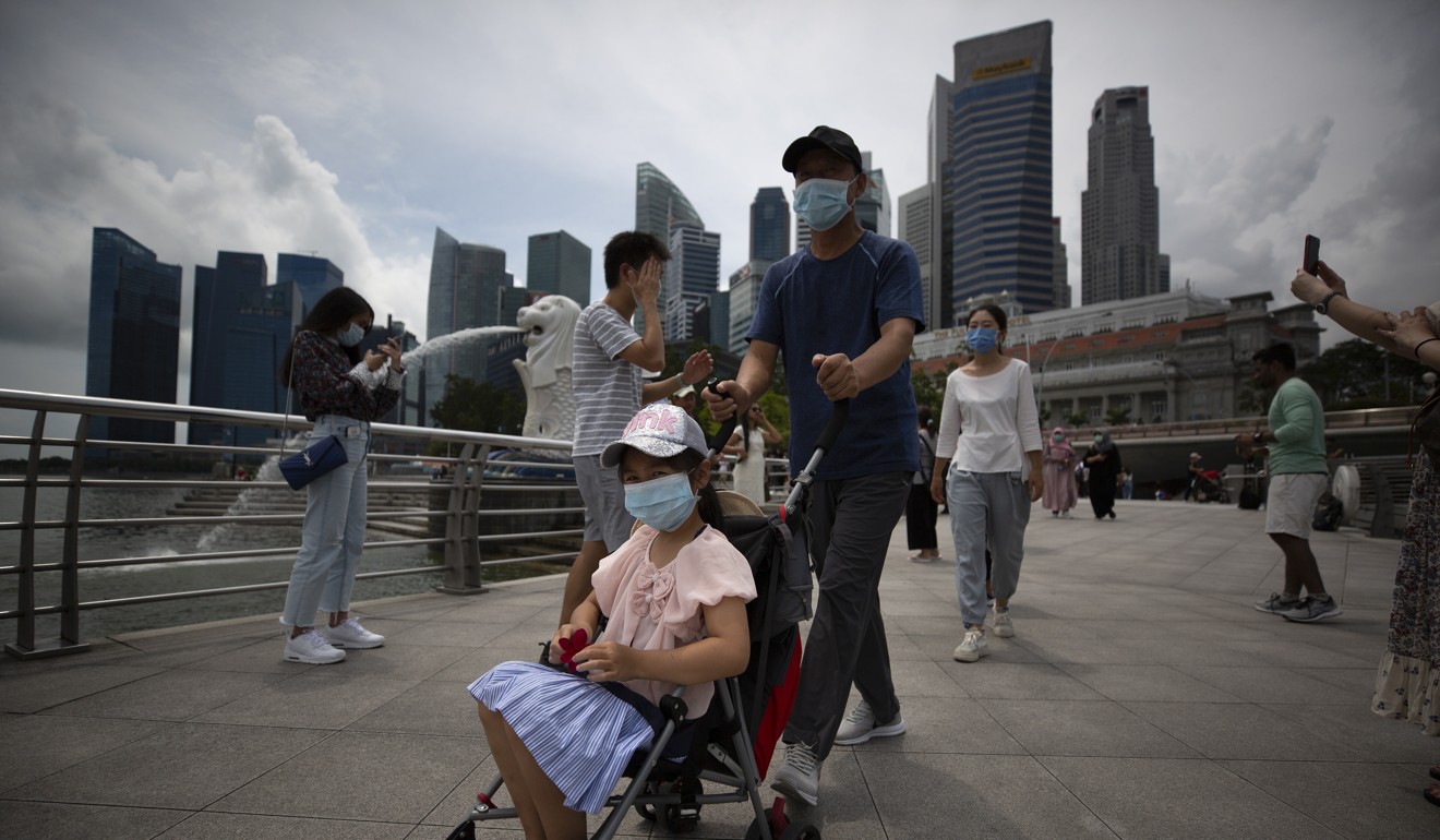 Tourists wearing face masks walk around Merlion Park in Singapore. Photo: EPA-EFE