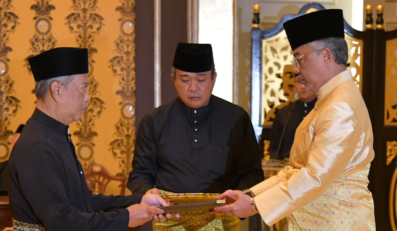 Malaysia's incoming Prime Minister Muhyiddin Yassin (left) receives documents from King