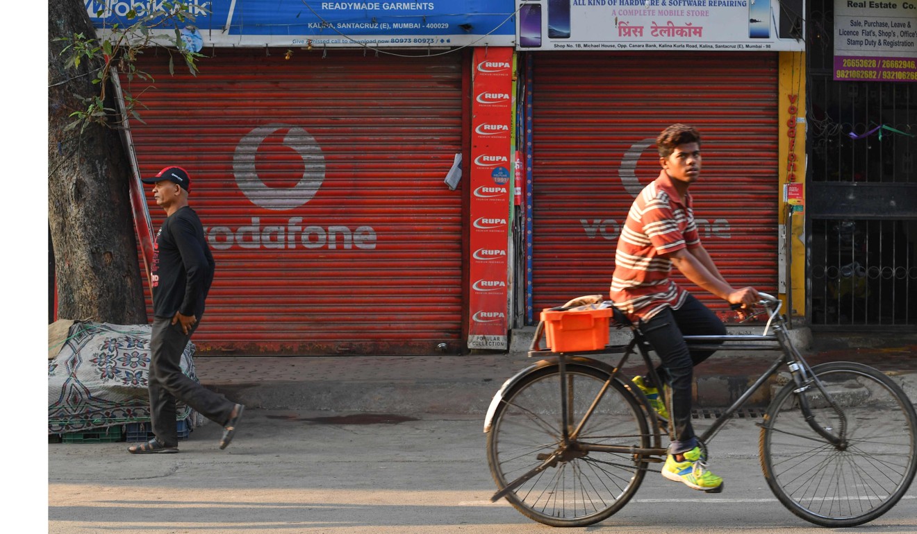 A man rides past a shop advertising telecoms company Vodafone in Mumbai. Photo: AFP