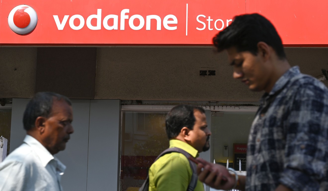 Pedestrians walk past a Vodafone store in Mumbai. Photo: AFP