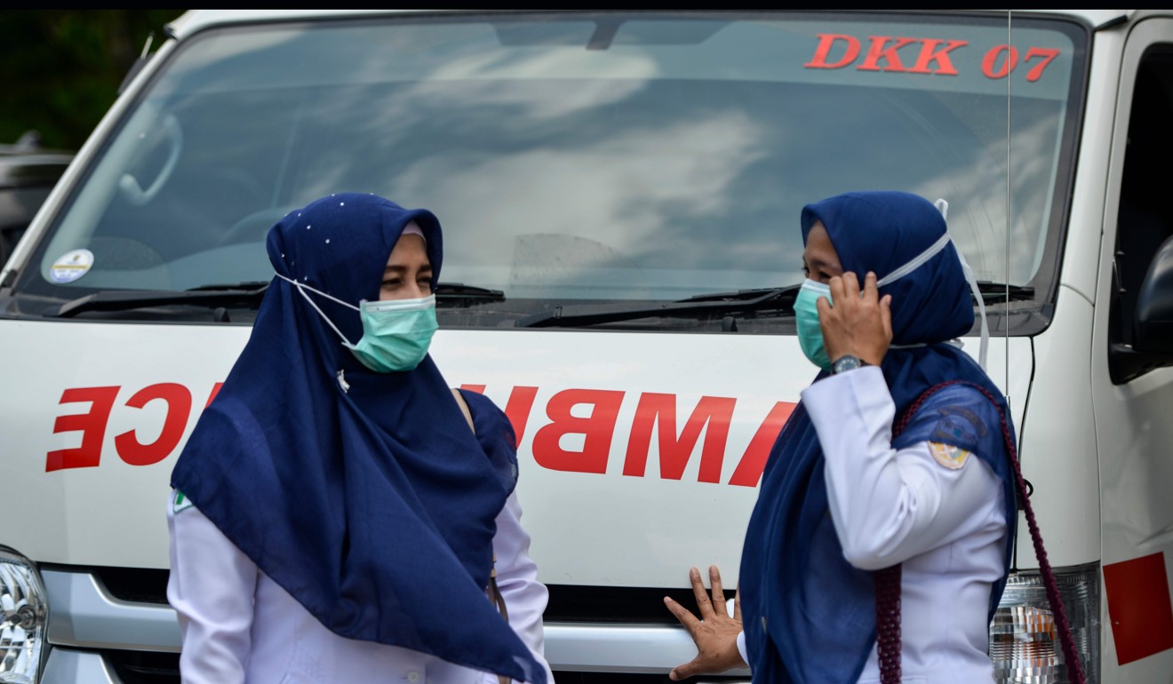 Indonesian health workers wearing face masks stand in front of an ambulance. Photo: AFP