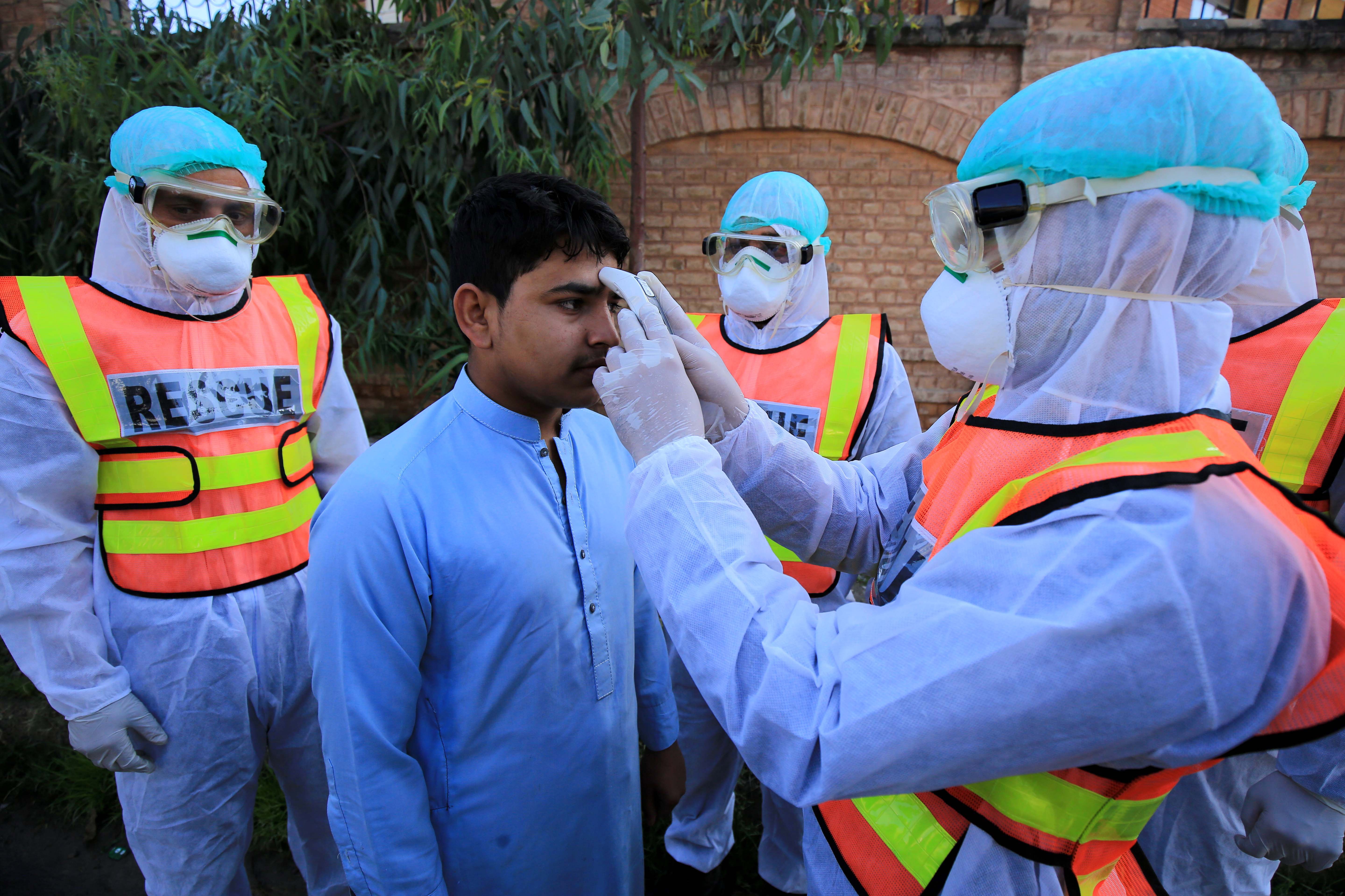 Pakistani health workers check the body temperature of a person during a drill conducted to improve efforts to contain the spread of coronavirus, as cases in neighbouring Iran soar. Photo: EPA-EFE