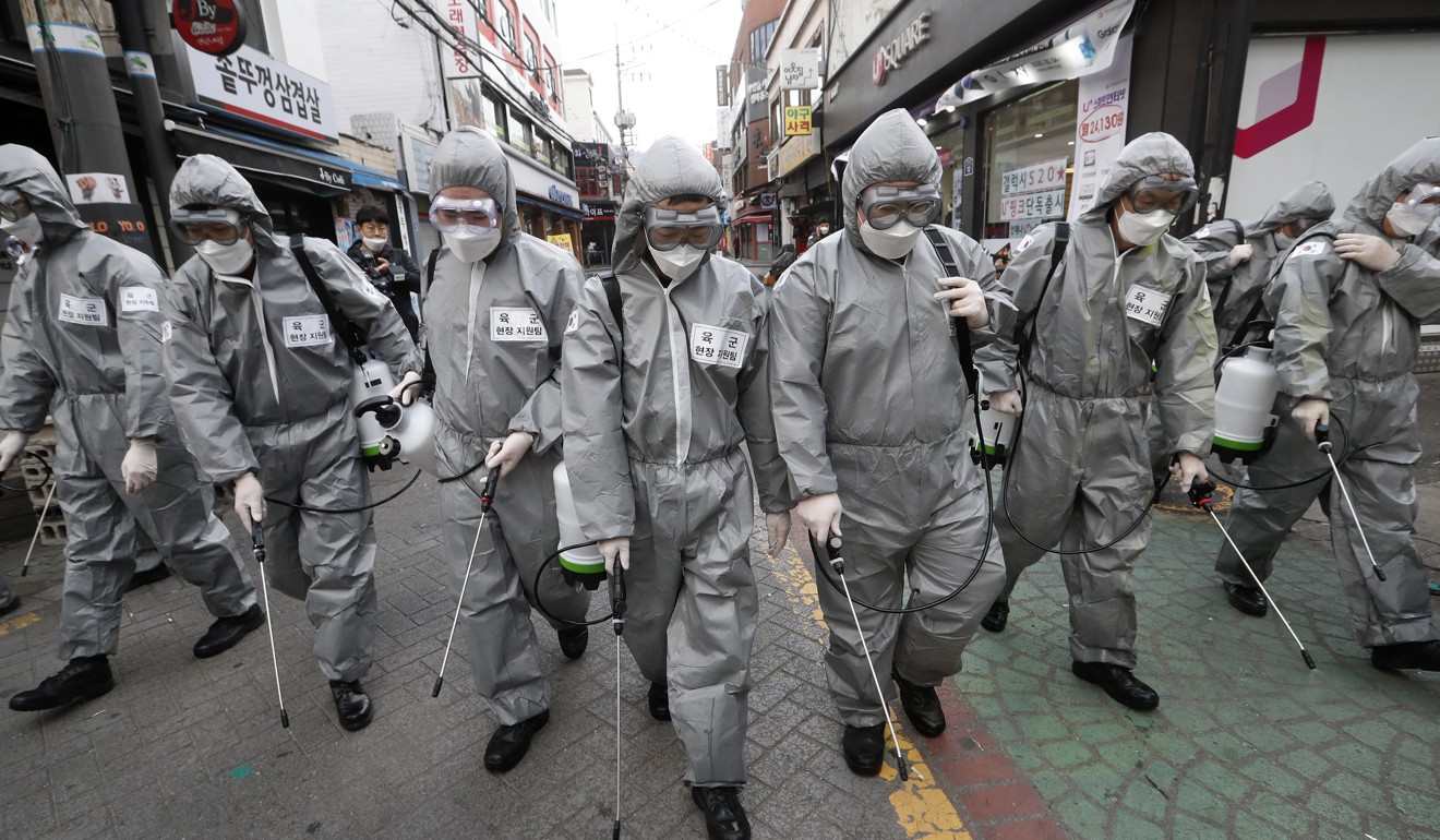 South Korean soldiers wearing protective suits spray disinfectant as a precaution against the new coronavirus at a shopping street in Seoul on Wednesday. Photo: AP
