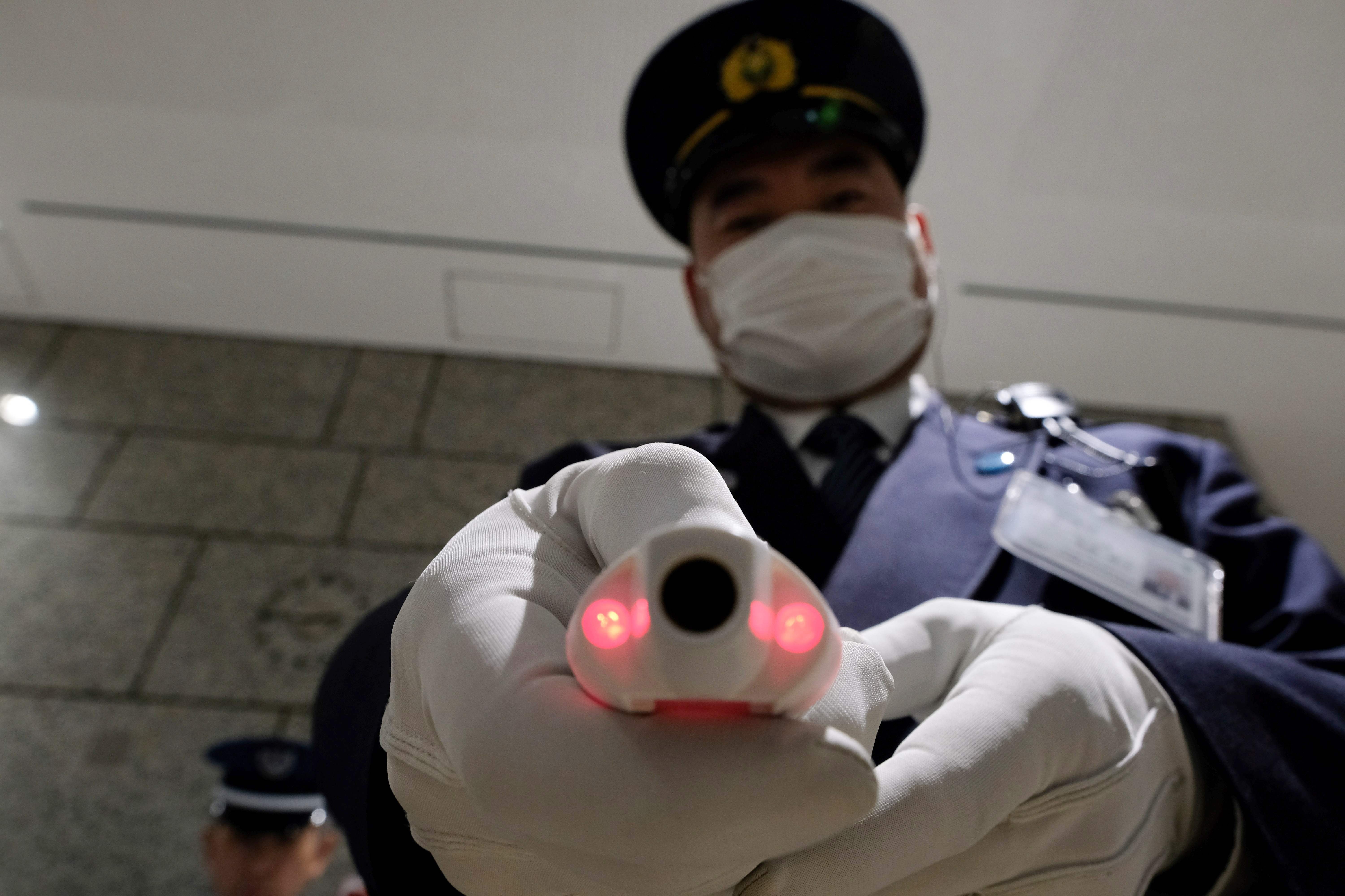 A security guard shows a body temperature measuring device at the reception of a government office in Tokyo. Photo: AFP