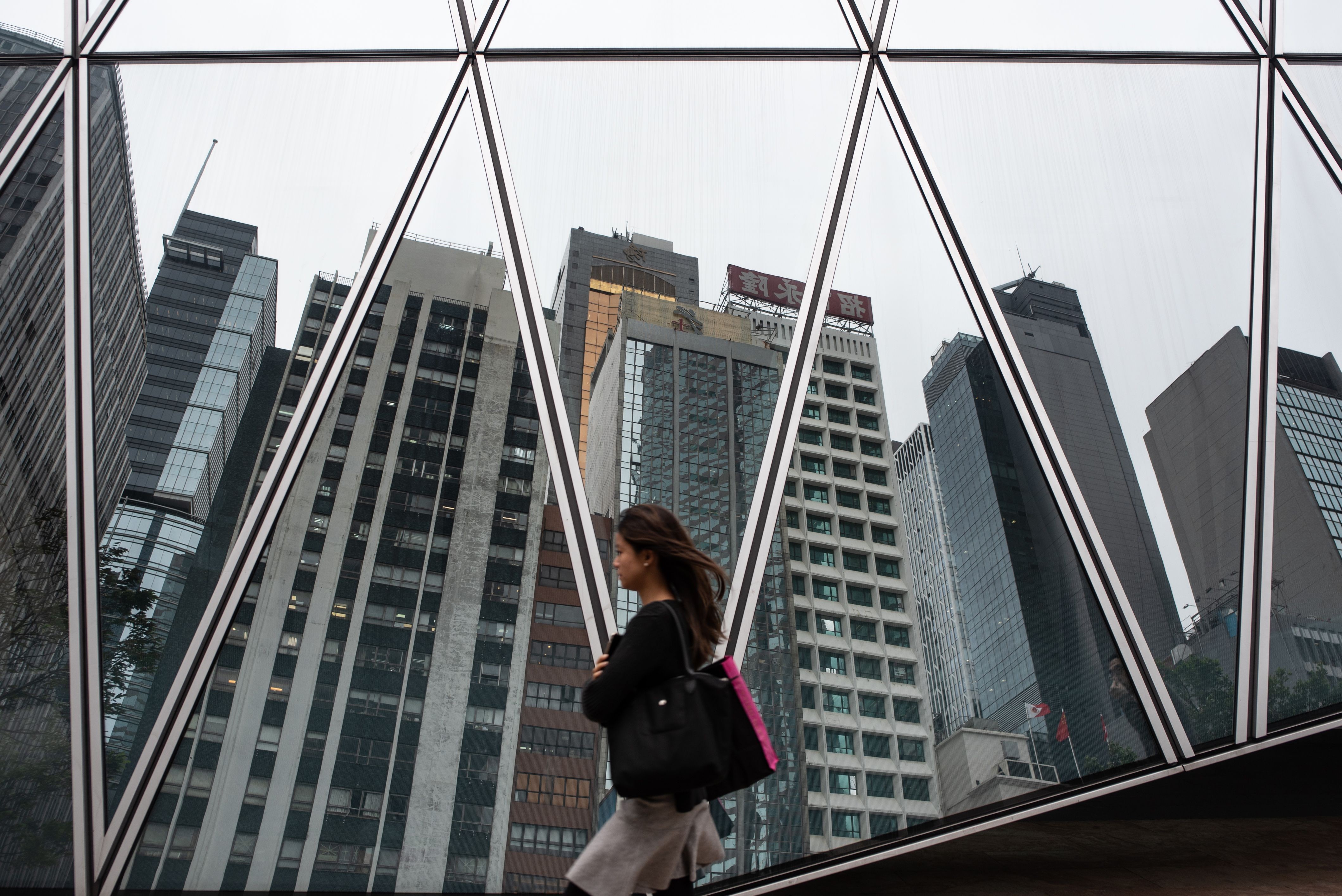 A woman walks past a reflection of the skyline of Hong Kong’s central business district on May 8, 2019. Hong Kong is near the top of US fund research firm Morningstar’s global gender diversity rankings for fund managers and chartered financial analysts, well ahead of Britain and the US. Photo: AFP