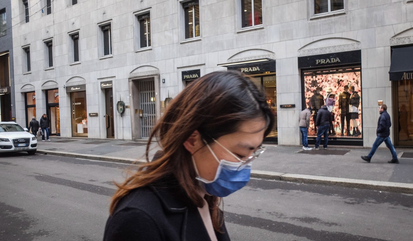 A woman wearing a protective face mask walks along one of the streets of the Milan's fashion district. Photo: