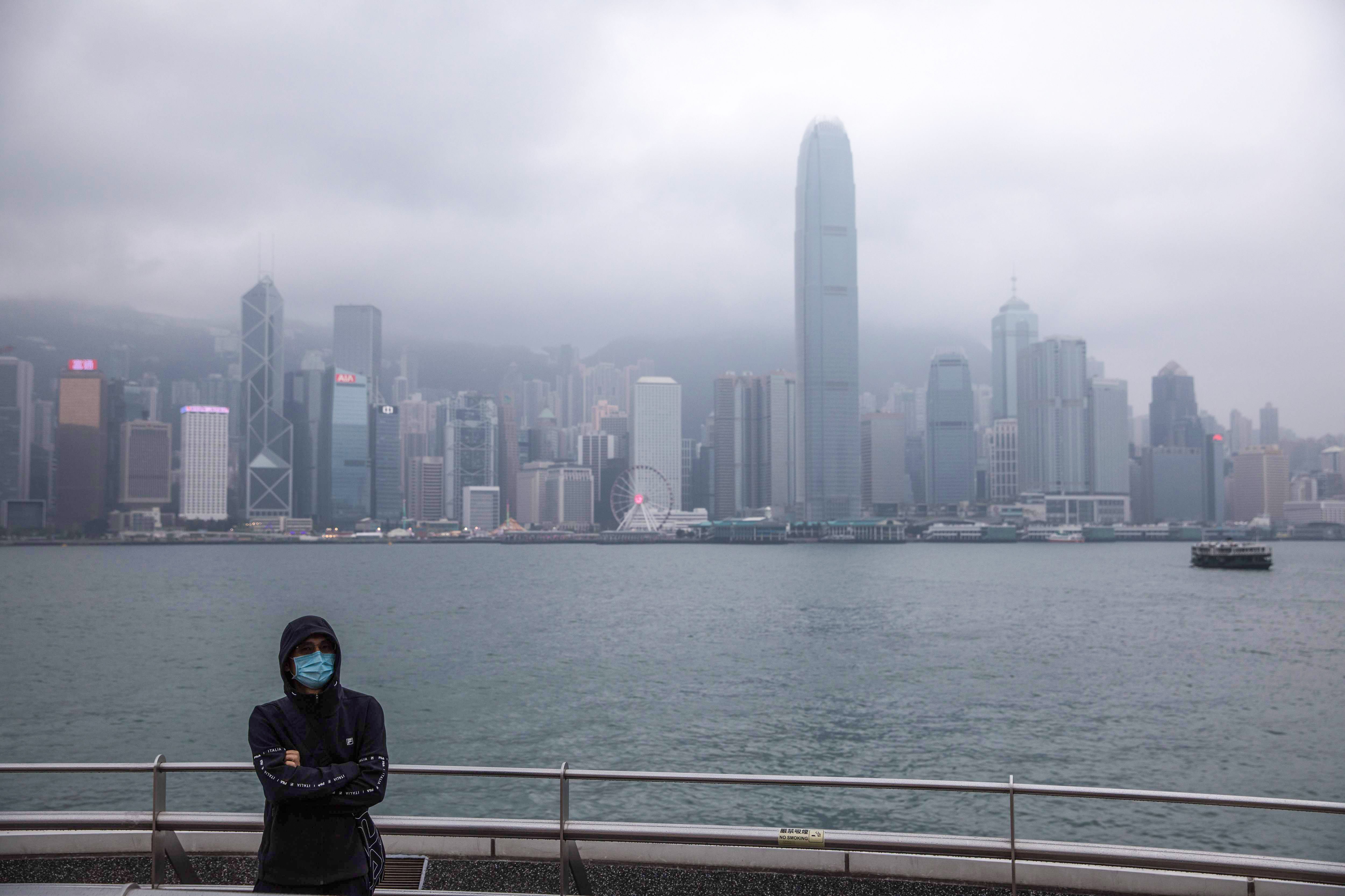 A man wearing a face mask is flanked by the Hong Kong skyline in Tsim Sha Tsui on January 25. The coronavirus epidemic has emptied streets in some of Hong Kong’s busiest areas. Photo: AFP