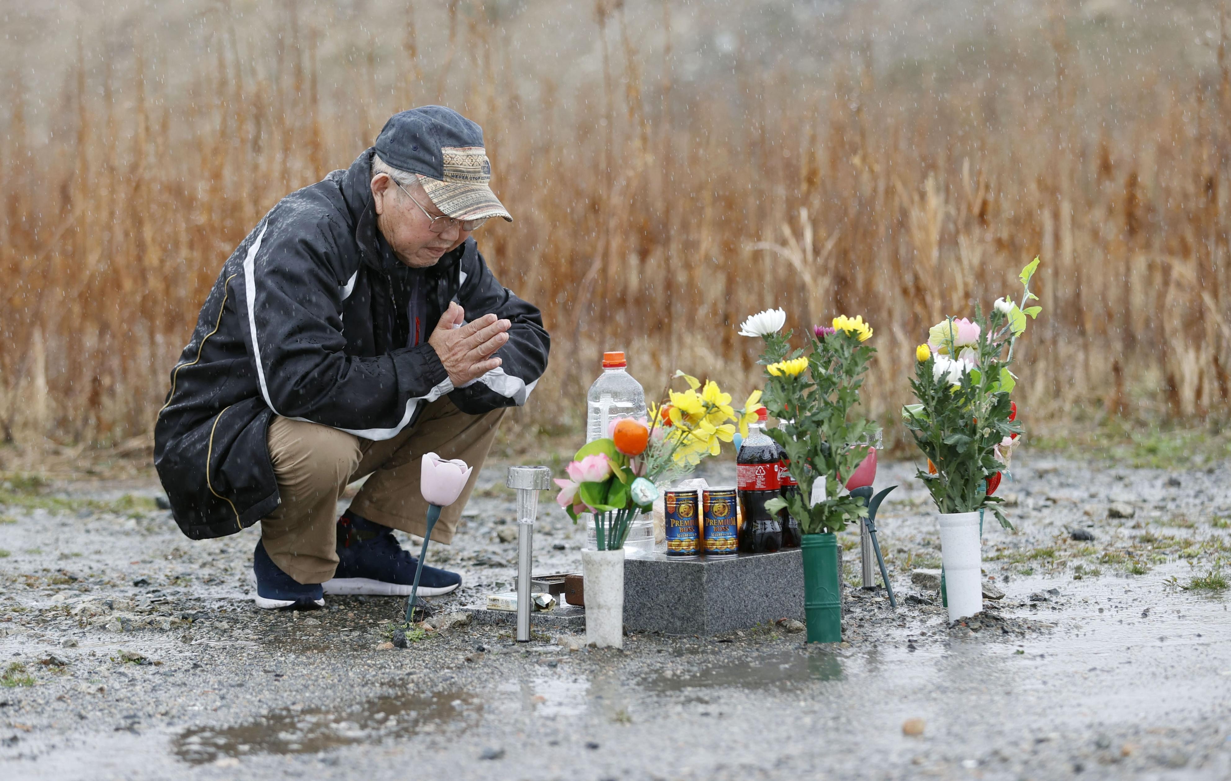 A bereaved father mourns his lost son, who went missing in the tsunami, at a memorial in Namie, Fukushima Prefecture, on Monday. Photo: Kyodo