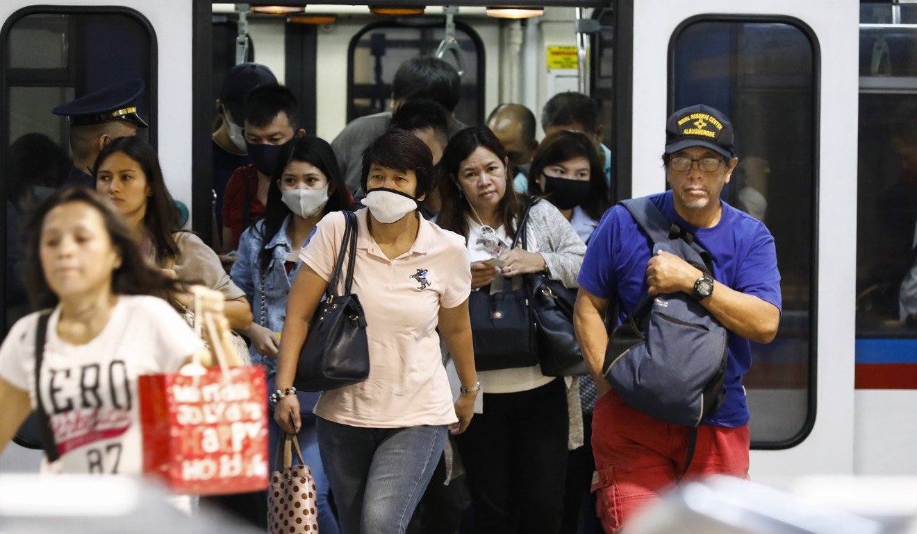 Some commuters seen in protective masks disembark from a train in Quezon City on Tuesday. Photo: EPA-EFE