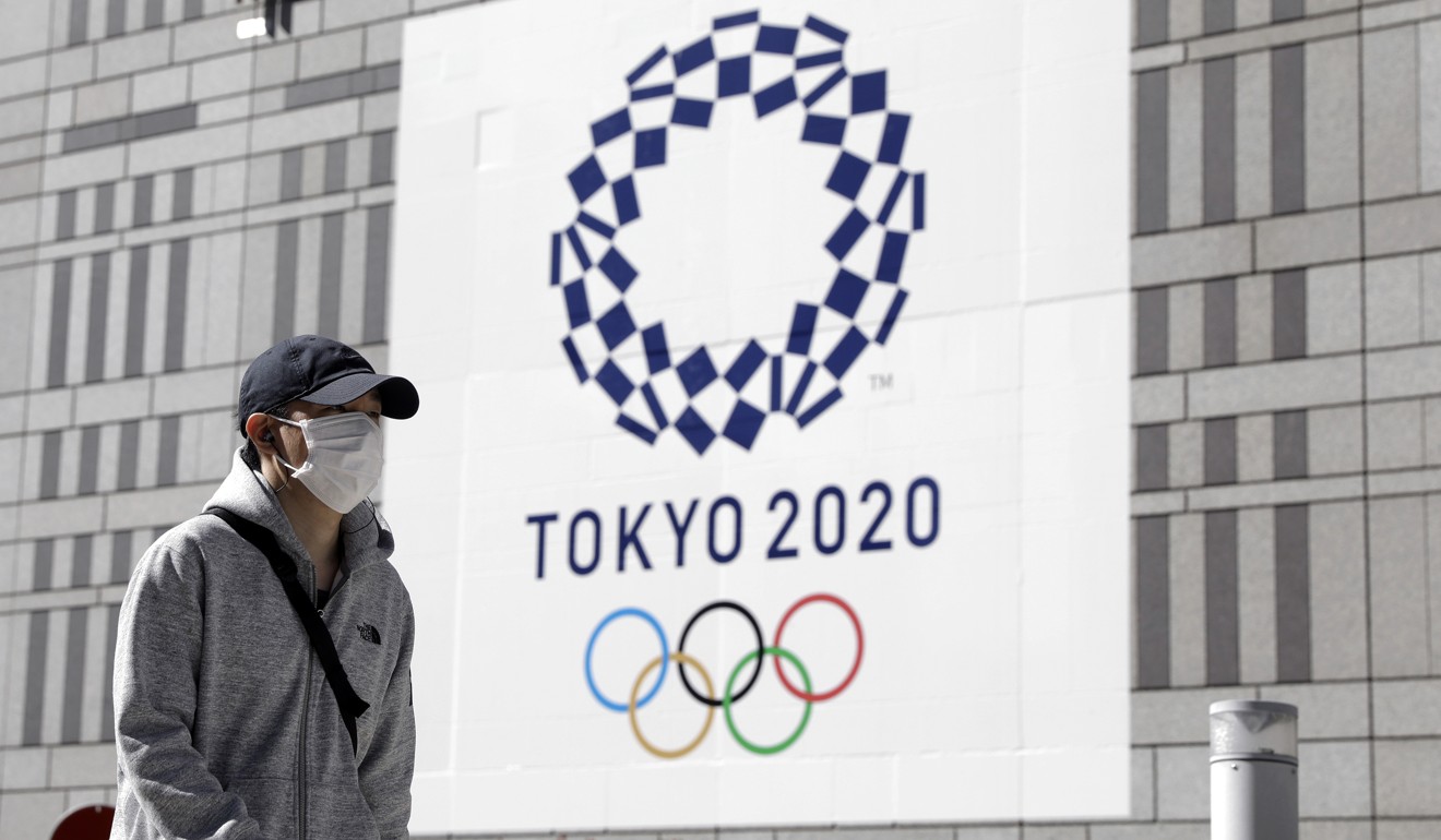A pedestrian wearing a protective face mask walks past a banner featuring the emblem for the Tokyo 2020 Games, which are less than five months away. Photo: Bloomberg