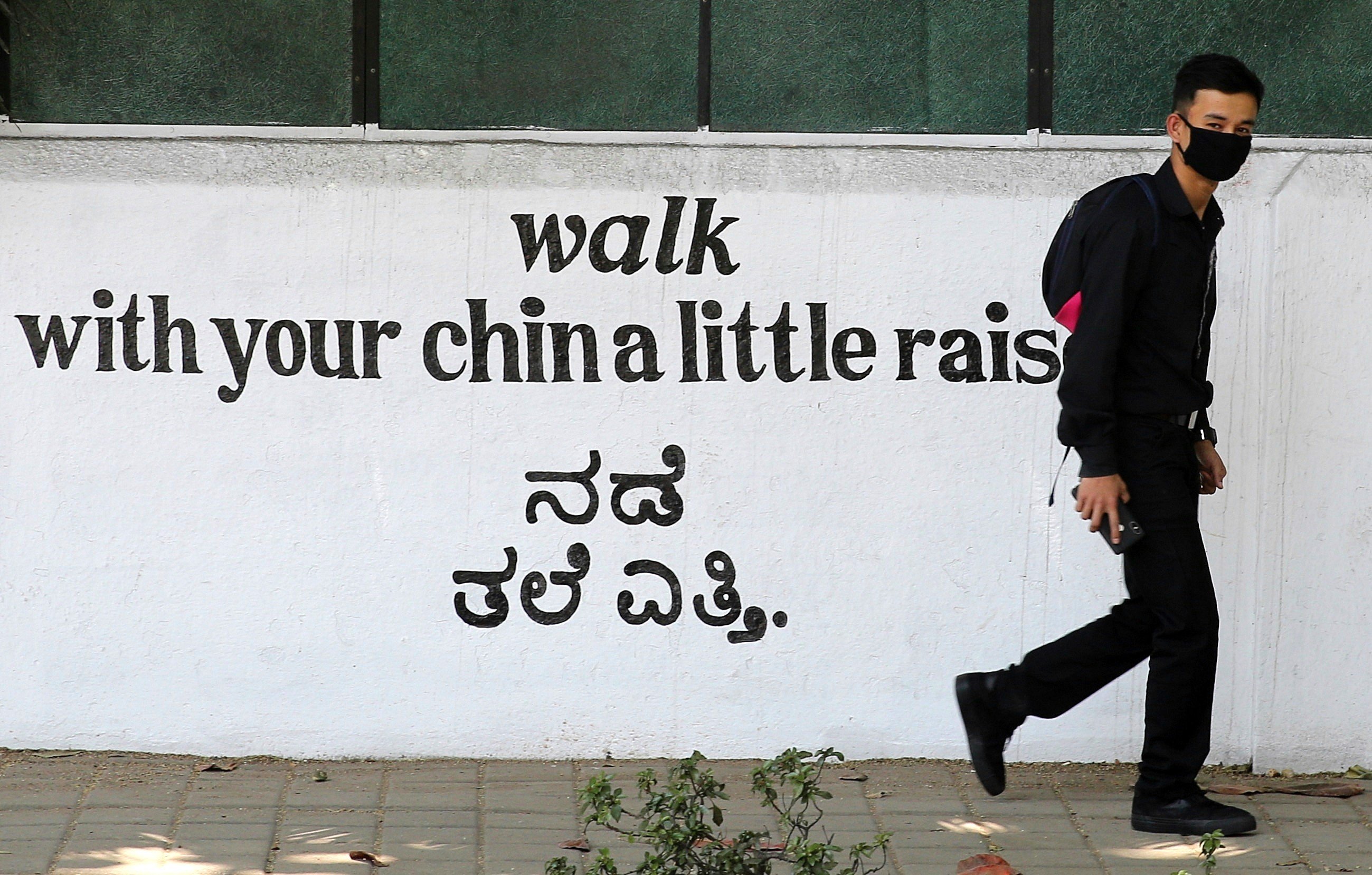 A person wears protective mask as he walks in front of the closed shopping centre in Bangalore, India. Photo: EPA