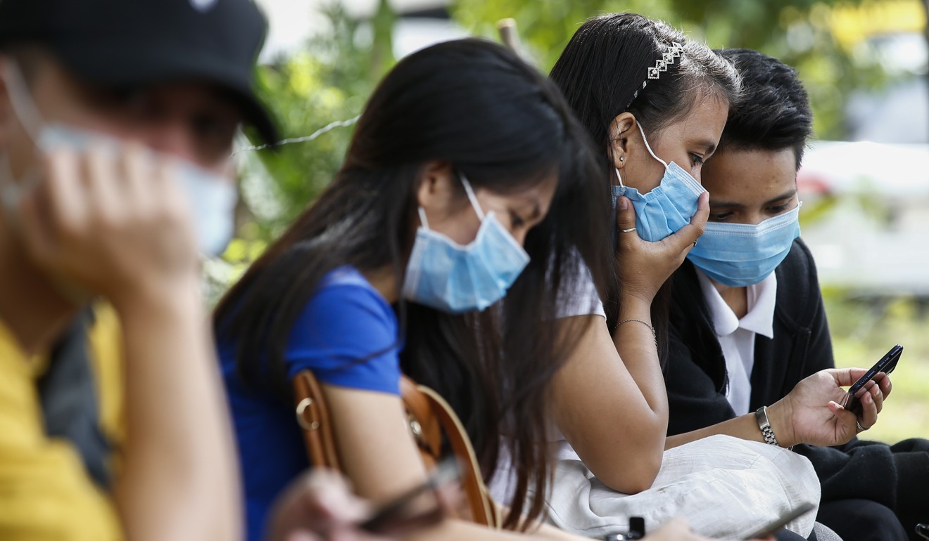 Filipinos wear protective masks while using their mobile phones at Quezon City Hall. Photo: EPA