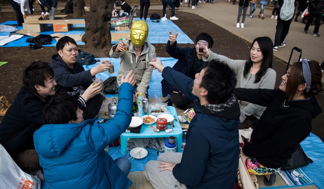A group of colleagues raise their glasses for a toast as they picnic under cherry blossoms in a park in Tokyo in 2017. Photo: AFP