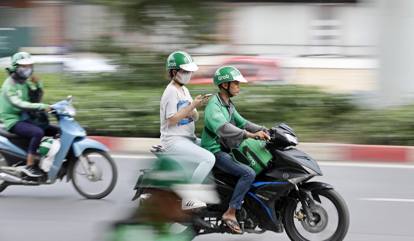 A GrabBike driver and his passenger ride in Hanoi, Vietnam. Photo: EPA