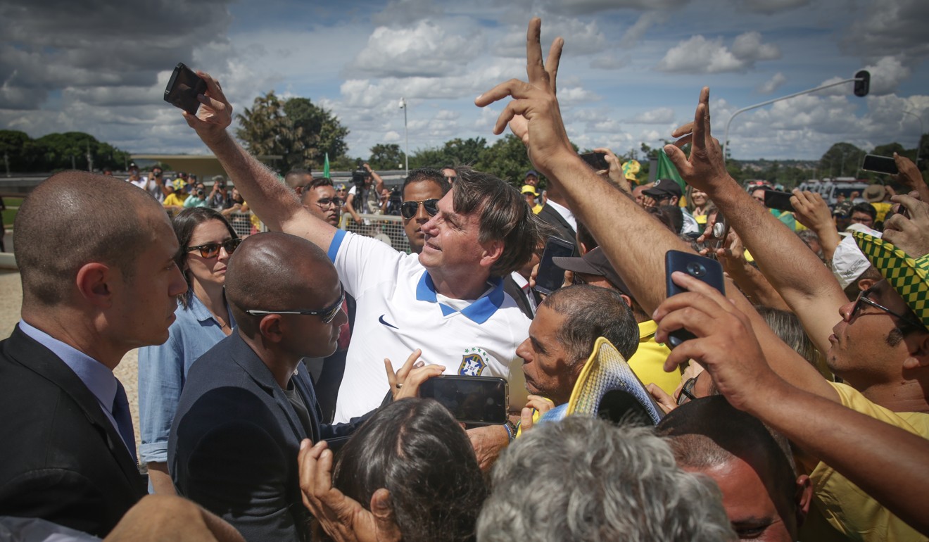 Not avoiding crowds: Jair Bolsonaro, Brazil’s president, takes a selfie with supporters. Photo” Bloomberg
