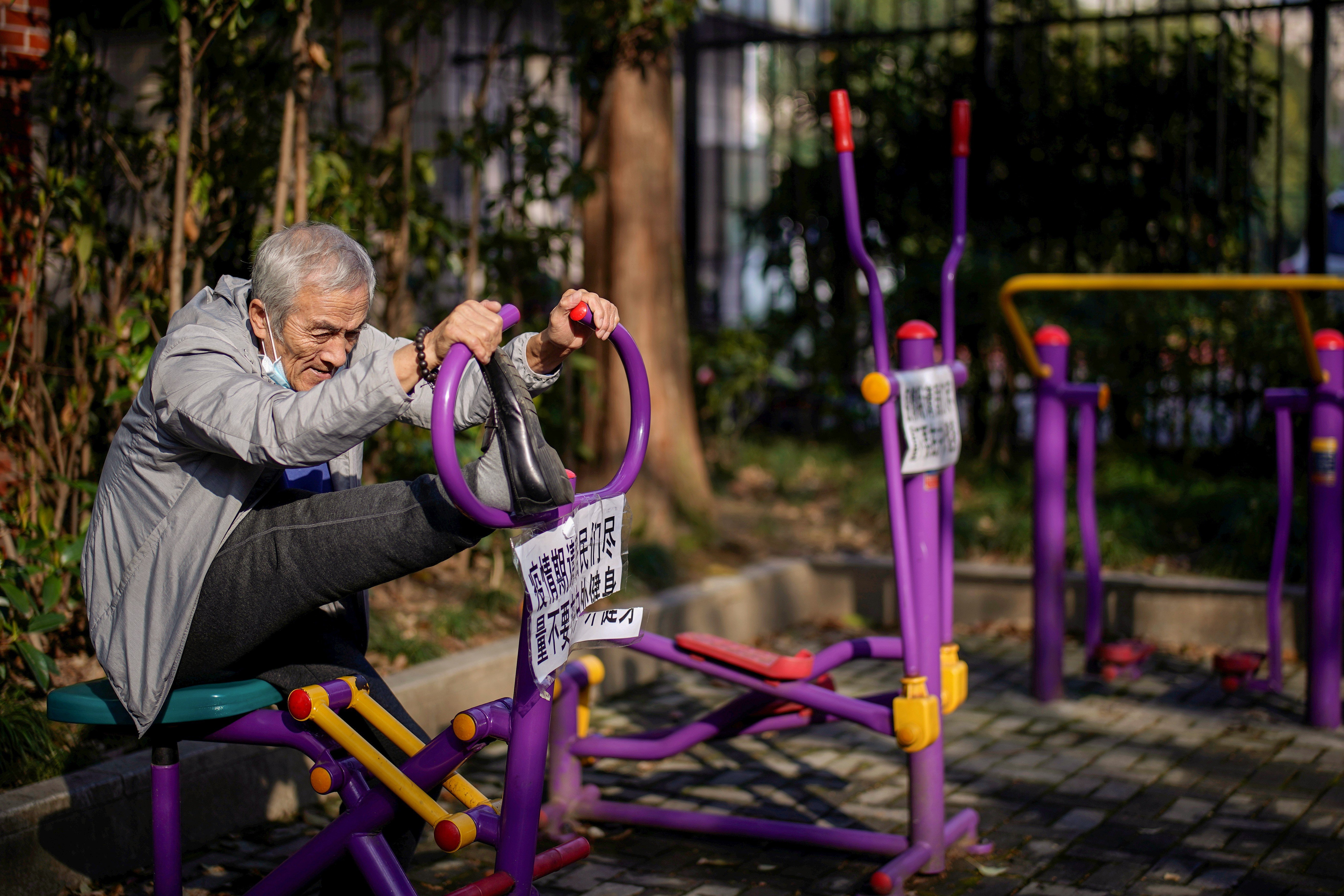 An elderly man stretches on a machine, with a sign advising residents to avoid exercising outdoors during the coronavirus outbreak, at a park in Shanghai on March 12. Photo: Reuters