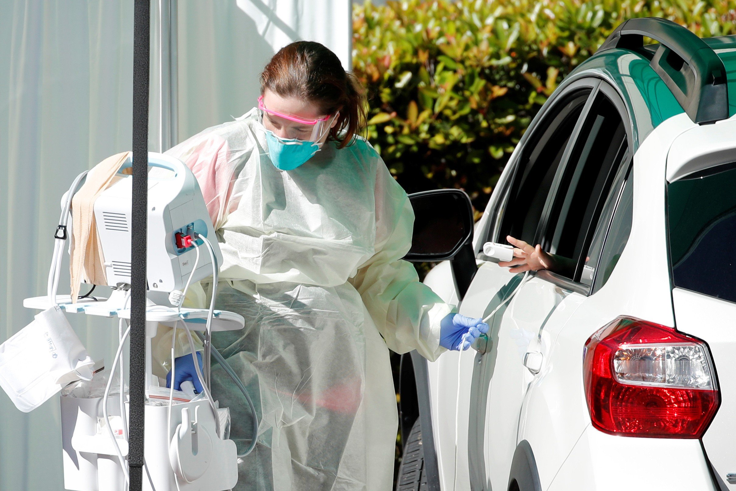 A healthcare worker attends to a person in the back of a vehicle at the Scripps Clinic as they provide drive-up care due to the global outbreak of the coronavirus disease (COVID-19) in La Jolla, California, U.S., March 17, 2020. REUTERS/Mike Blake