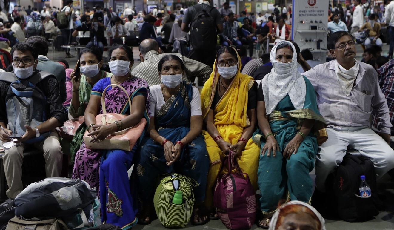 People wait at a Mumbai train station wearing protective masks on March 17, 2020. Photo: AP