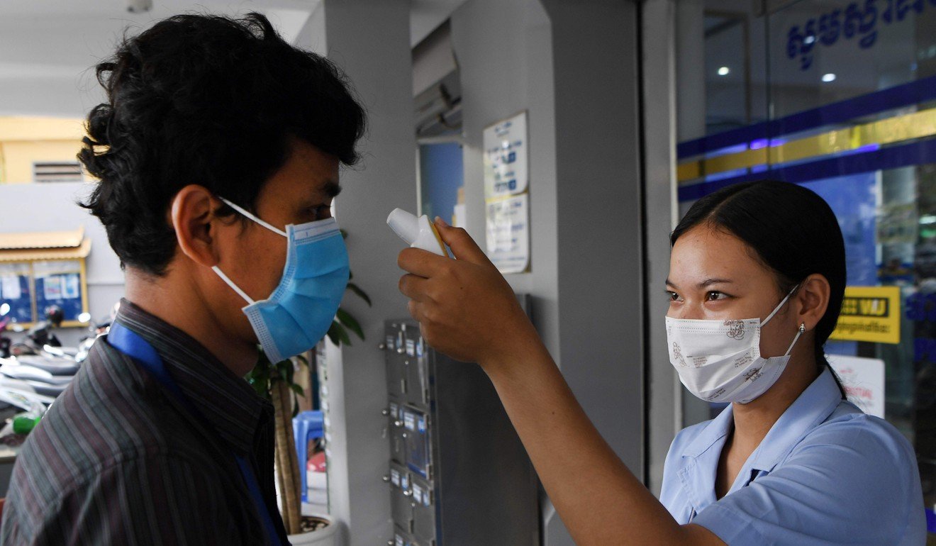 A man gets his temperature checked before entering a bank in Phnom Penh. Photo: AFP