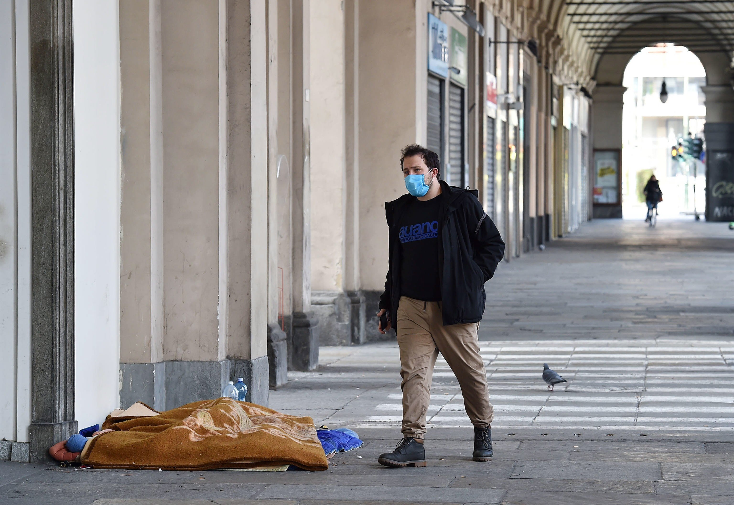 A man wearing a mask walks past a street sleeper in Turin, Italy, on March 17. Photo: EPA-EFE