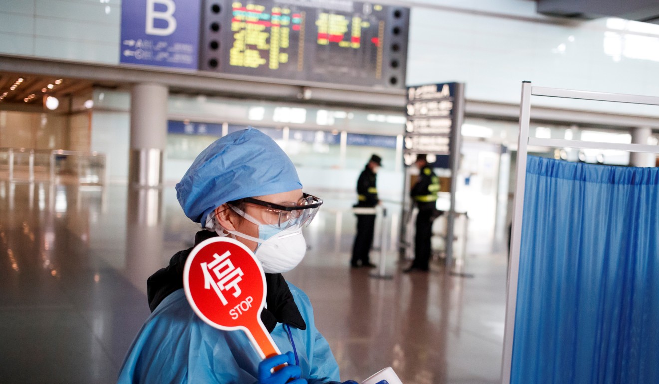 A staff member in protective gear at a temperature check station in the arrival hall at Beijing’s Capital Airport. Photo: Reuters