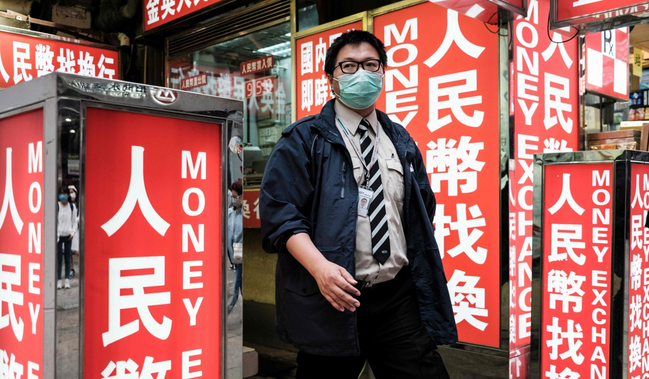 A security worker wears a face mask as he walks past a money exchange outlet in Hong Kong on March 1. Photo: Agence France-Presse