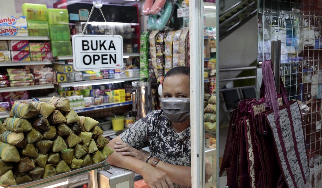 A snack vendor waits as his shop is disinfected in the wake of a coronavirus outbreak in Indonesia. Photo: AP