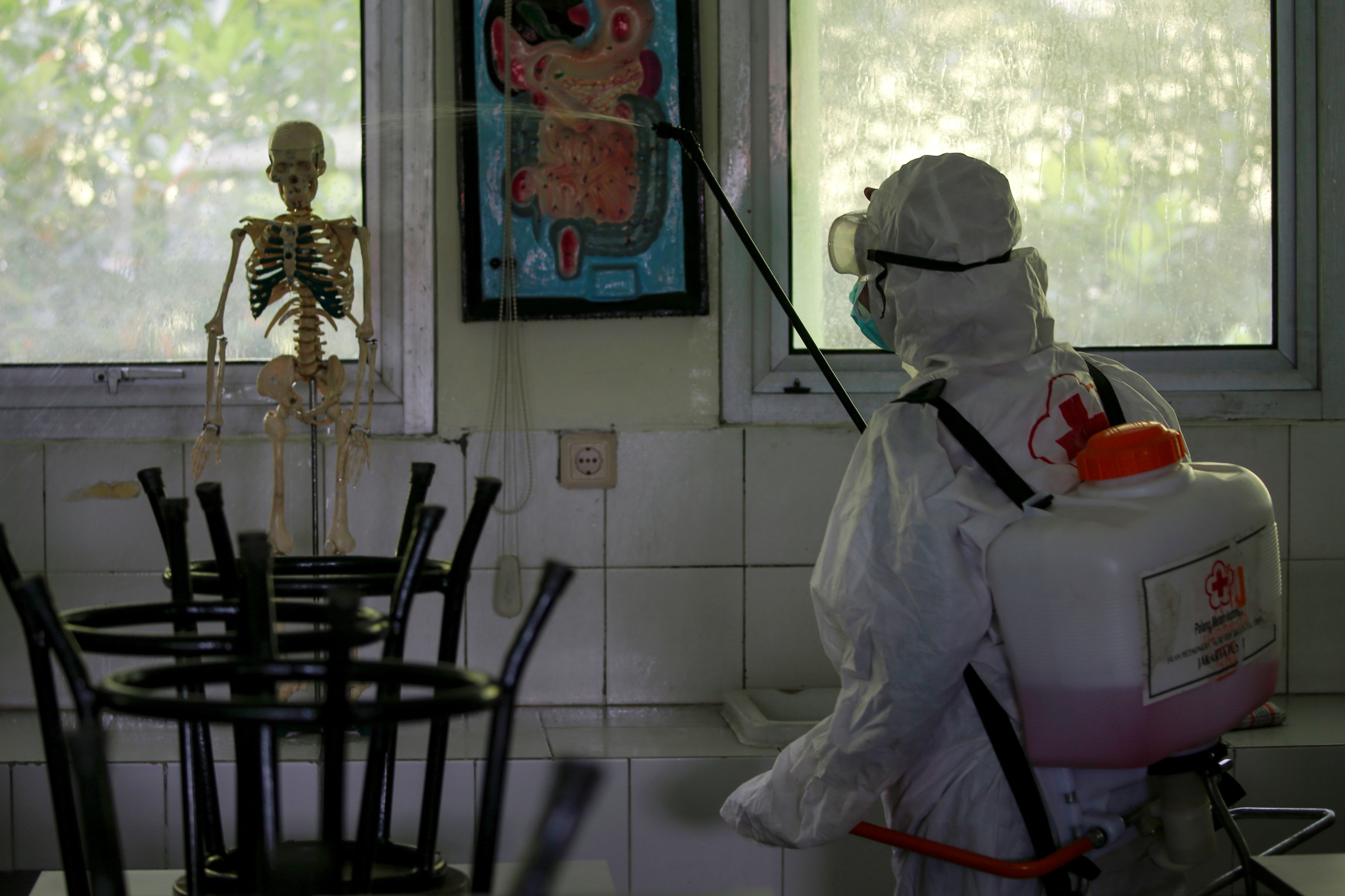 A volunteer from Indonesia’s Red Cross disinfects a school closed amid the spread of the coronavirus. Photo: Reuters