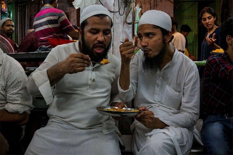 Two Indian men share a plate of biryani on the eve of Eid al-Fitr in New Delhi. Photo: Getty Images