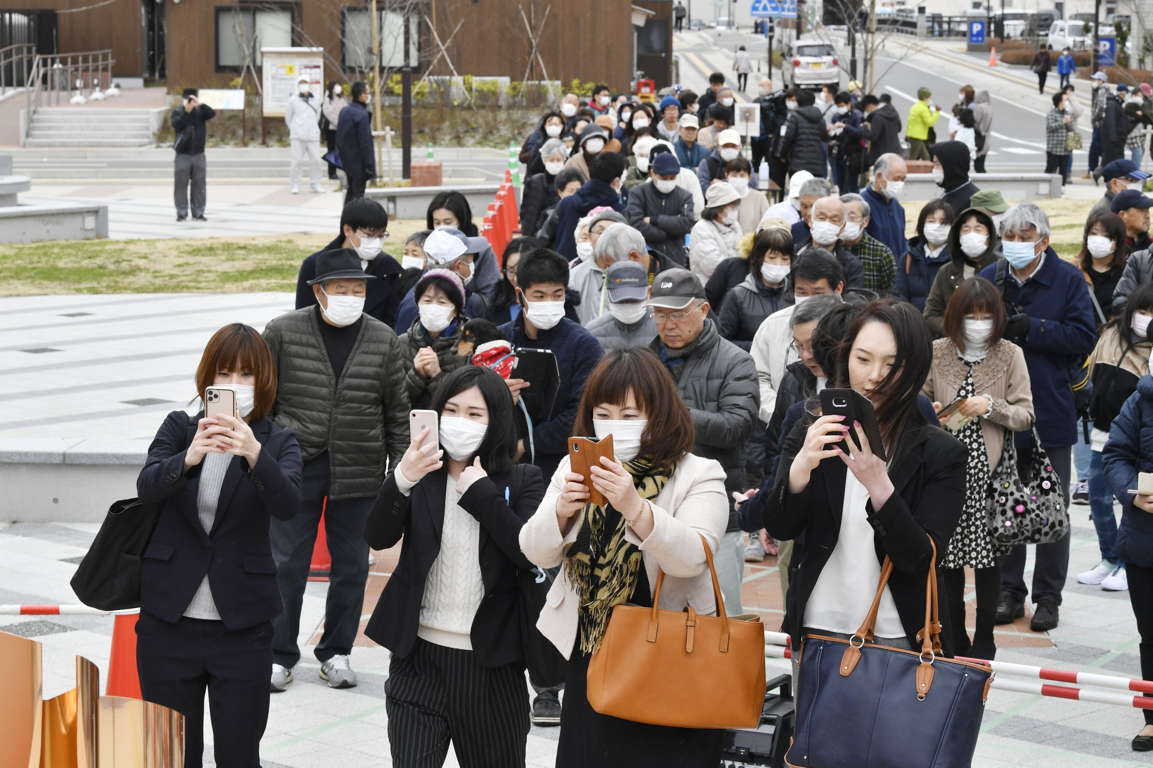 People visit to see the flame for this year’s Tokyo Olympics exhibited in Ofunato, Iwate prefecture, on Monday. Japan is under increasing pressuring to postpone the Olympic Games because of the Covid-19 pandemic. Photo: Kyodo