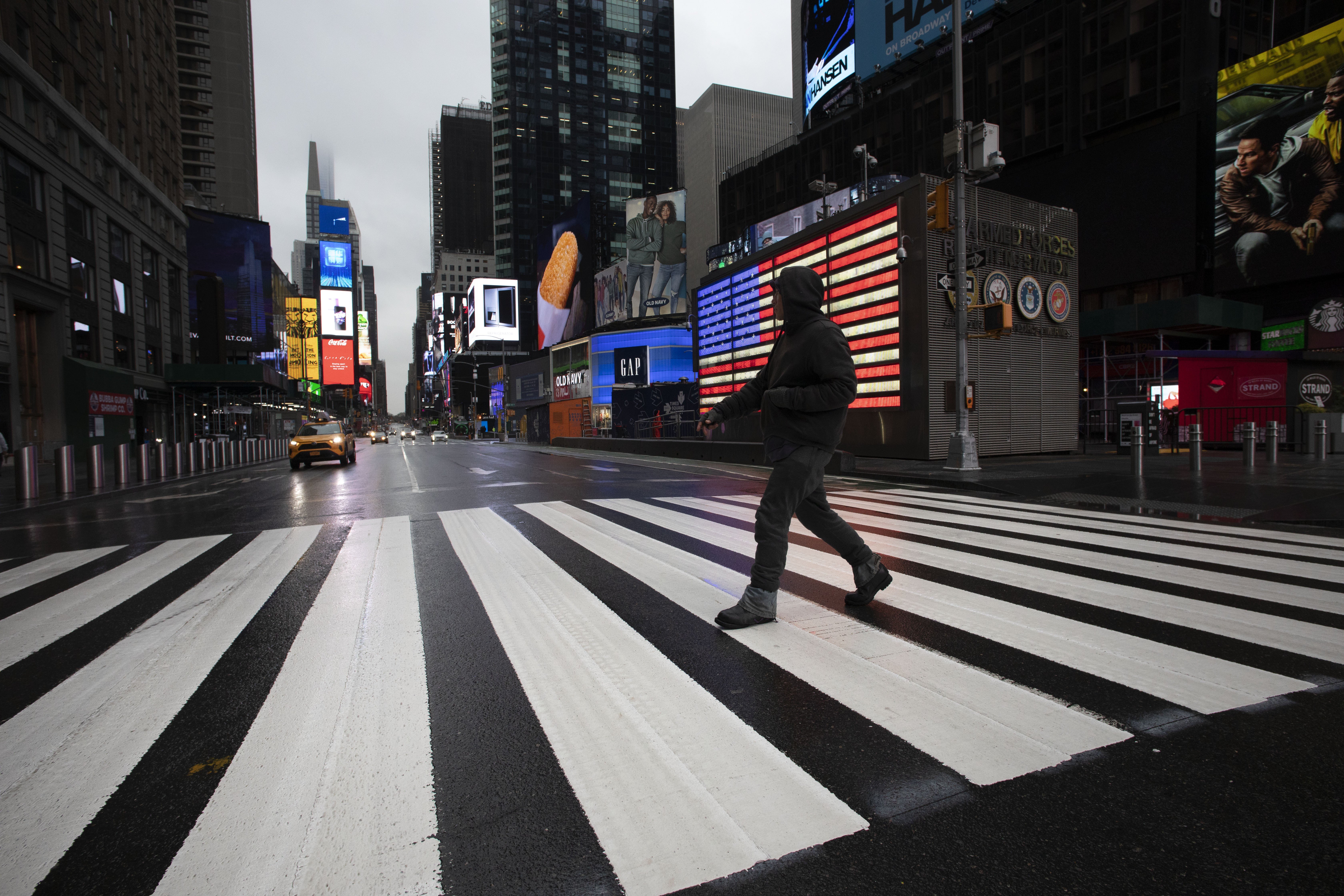A man crosses the street in a nearly empty Times Square in New York, which is usually very crowded on a weekday morning, on March 23. New York City, which alone has over 10,000 cases of infection, is on the verge of running out of medical supplies. Photo: AP