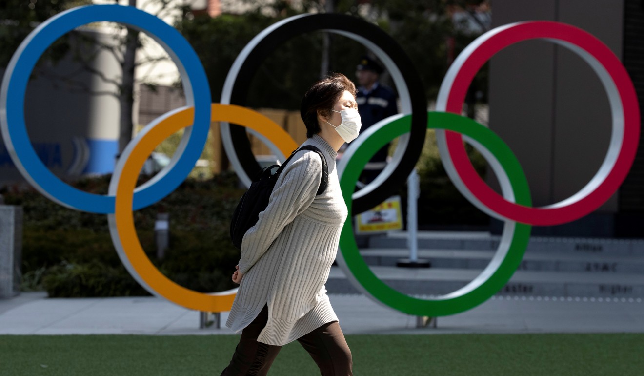 A woman wearing a protective face mask walks past the Olympic rings at the Japan Olympics Museum in Tokyo. Photo: Reuters
