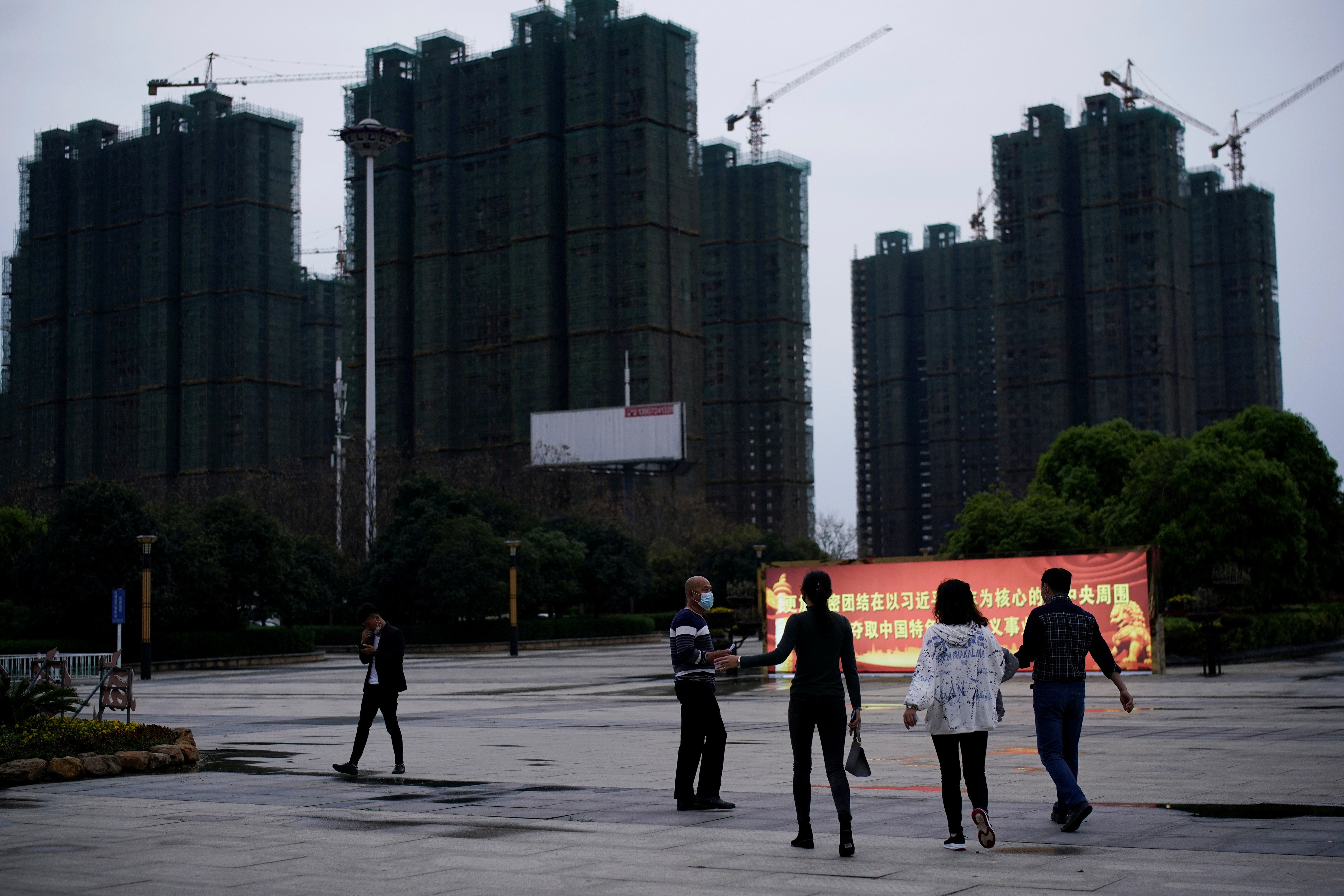 People in face masks near a propaganda sign in front of residential buildings under construction in Xianning, Hubei province, the epicentre of the coronavirus outbreak. Photo: Reuters