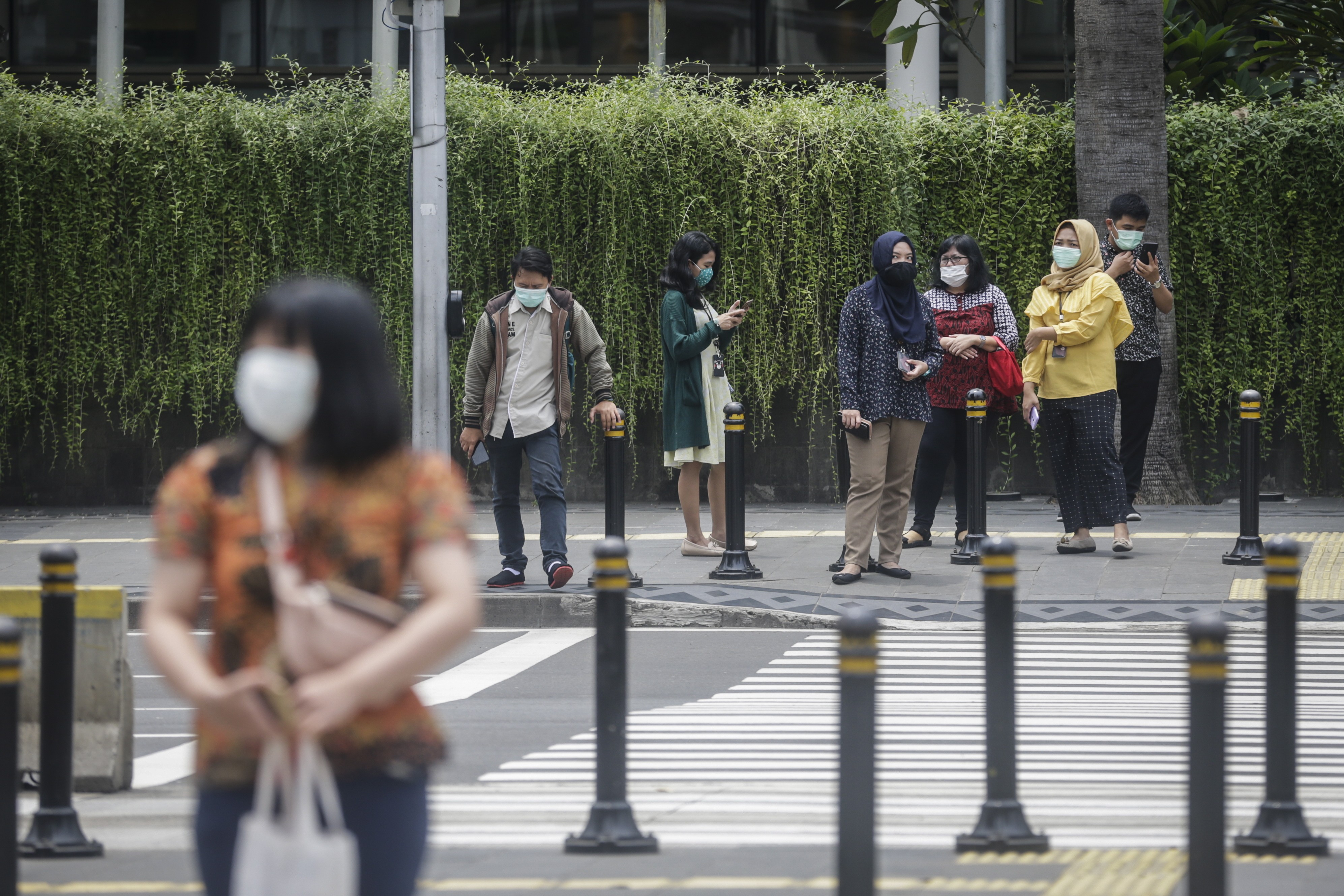 Indonesians wear protective face masks as they wait to cross the street in Jakarta. Authorities have urged people to avoid public gatherings, but many are still going to work, fearful that they might lose their jobs. Photo: EPA-EFE