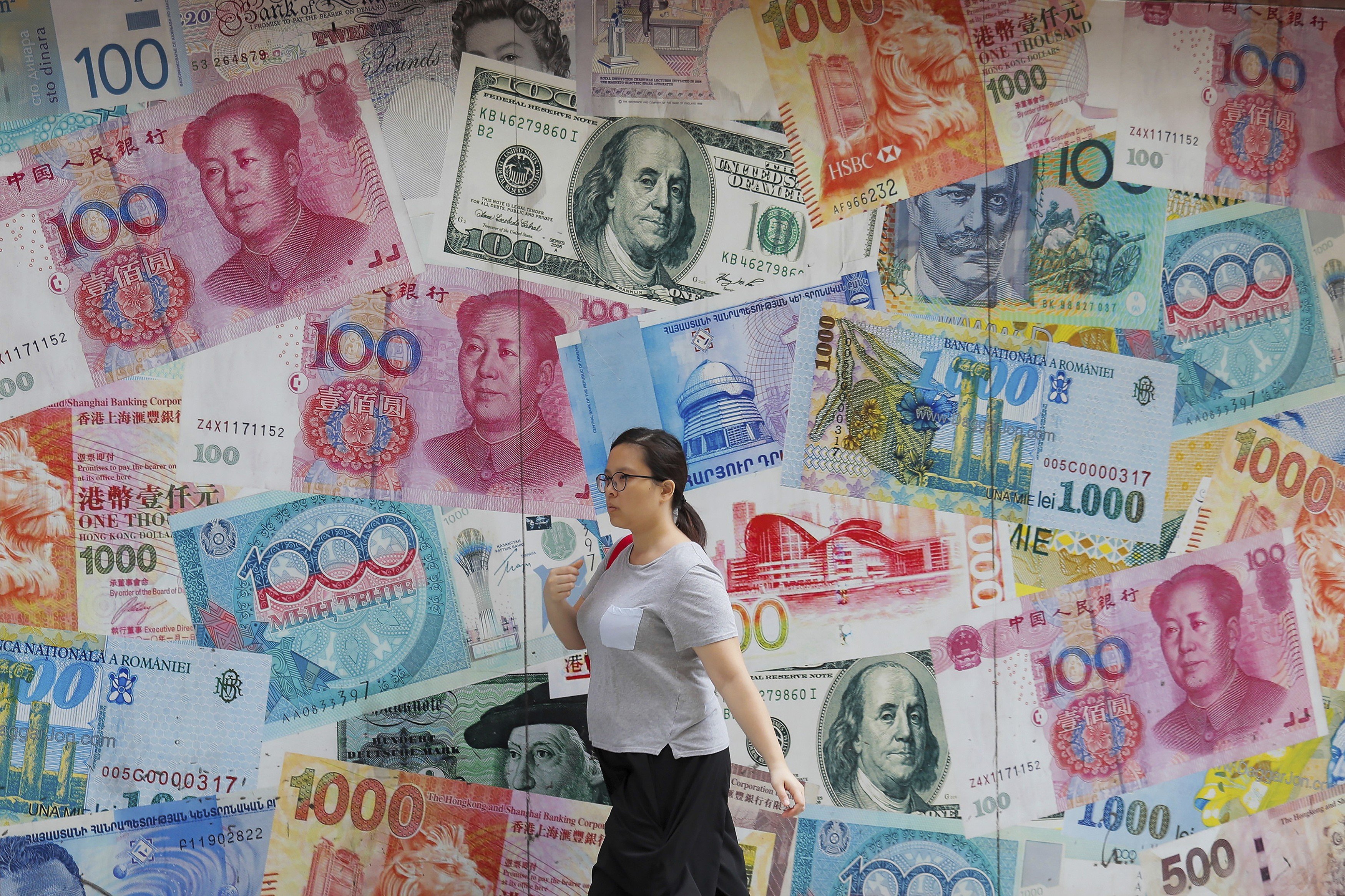 A woman walking by a money exchange shop decorated with currency notes of different countries at Central, a business district in Hong Kong on August 6, 2019. Photo AFP