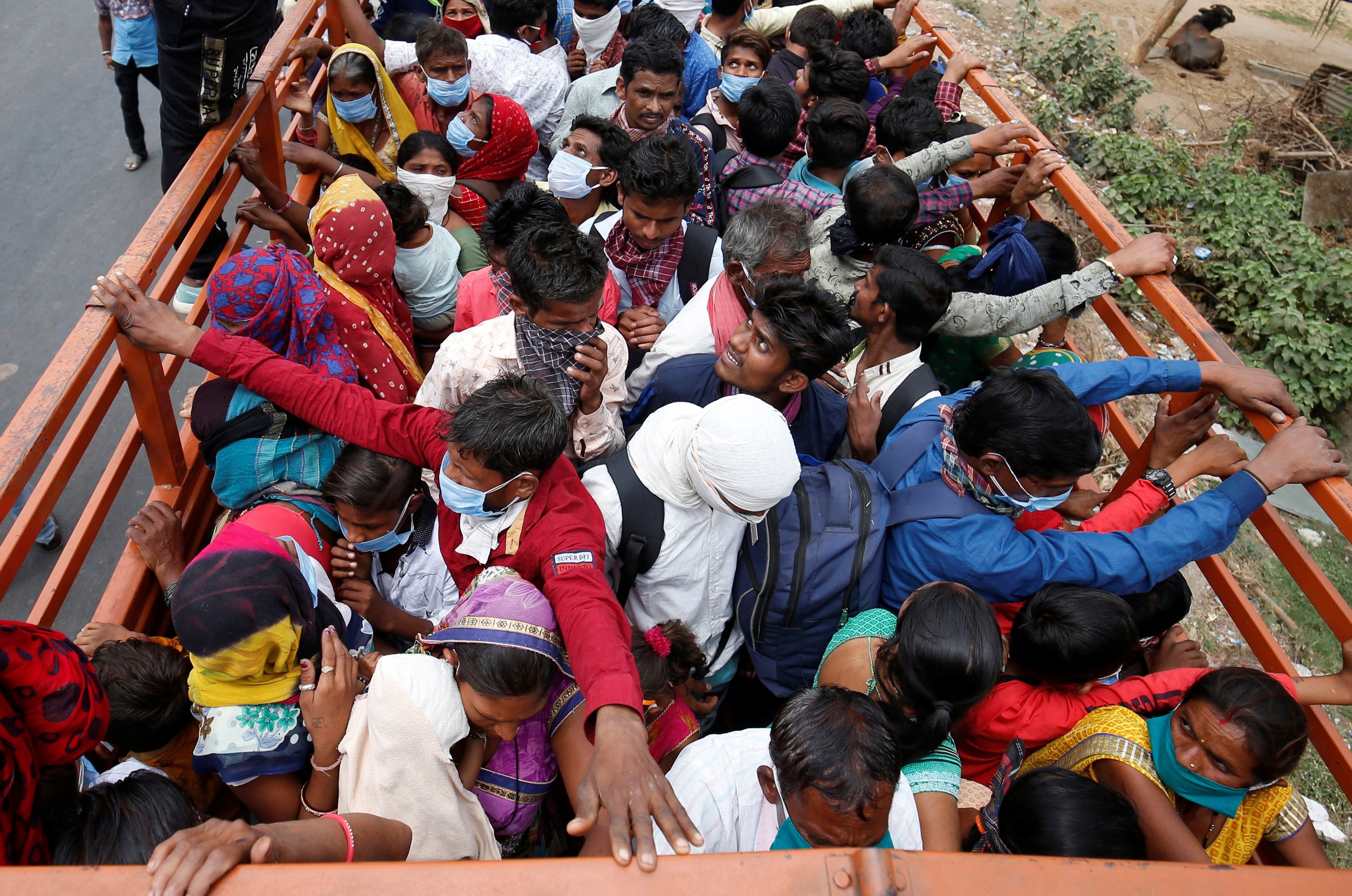 Migrant workers and their families board a truck in Ahmedabad on March 25 to return to their villages after India orders a 21-day nationwide lockdown to limit the spreading of Covid-19. Photo: Reuters