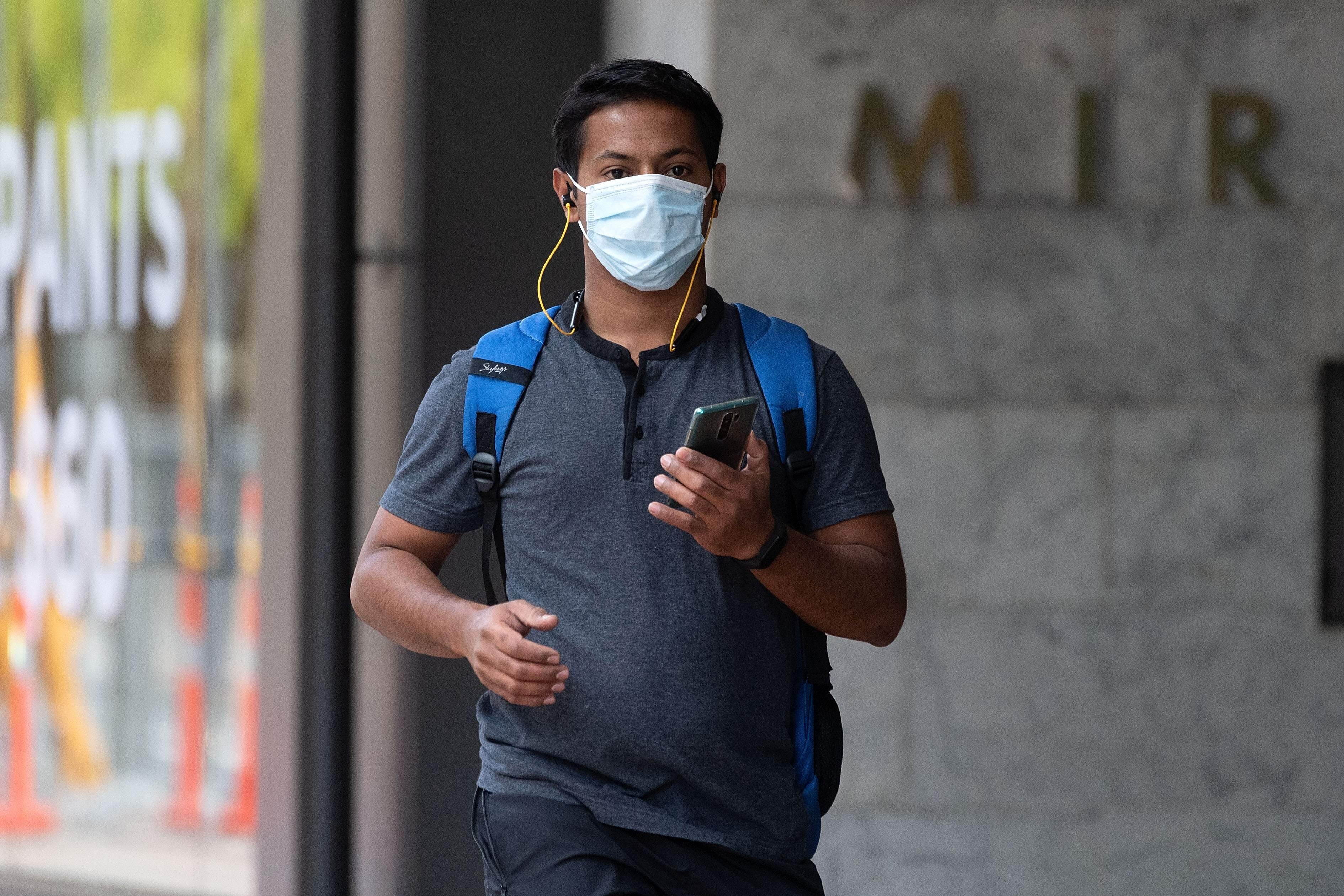 A man wearing a mask walks through a deserted Wellington CBD on March 26, 2020. Photo: AFP