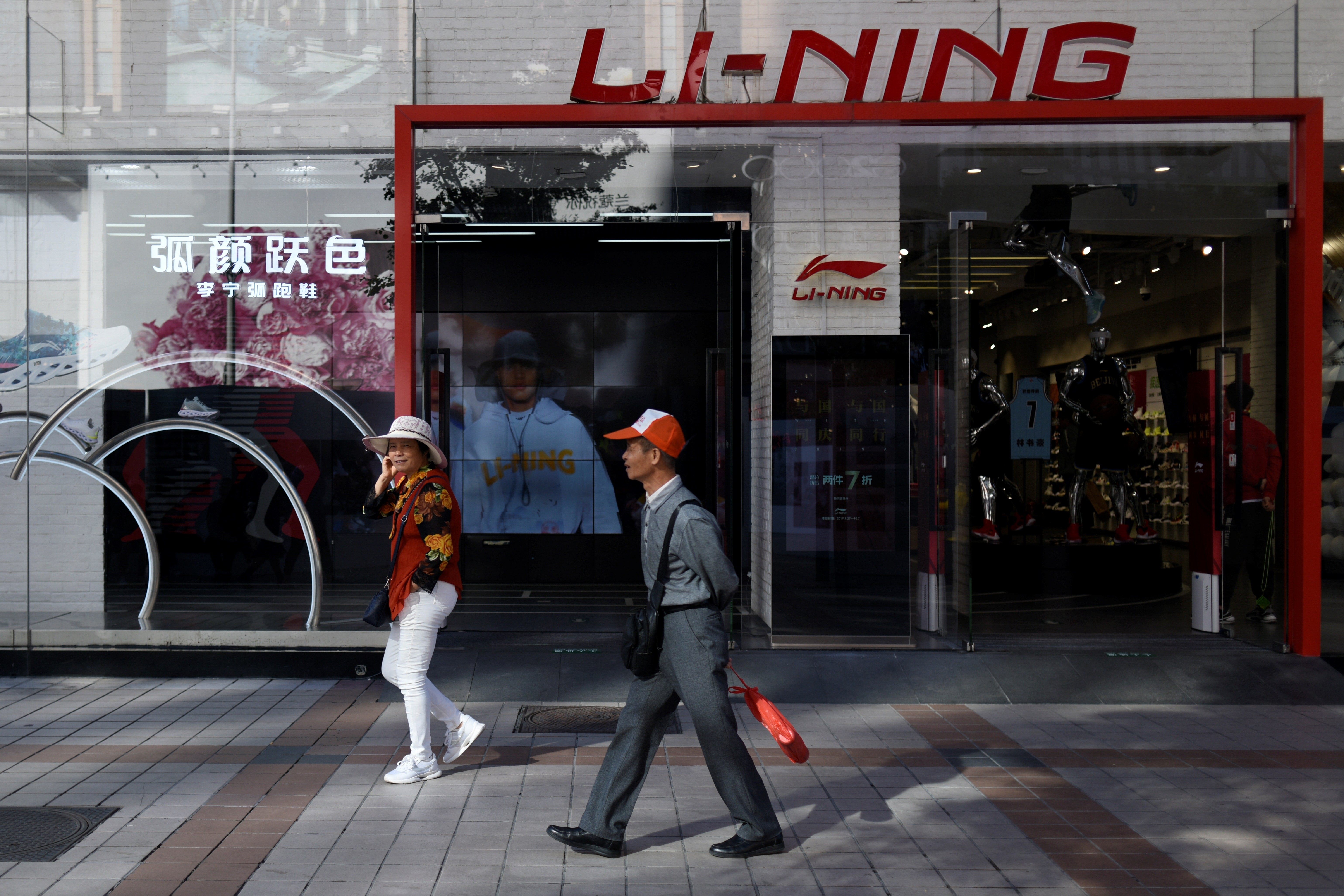 People walk past a Li-Ning store in Beijing on October 8, 2019. (Photo by WANG Zhao / AFP)
