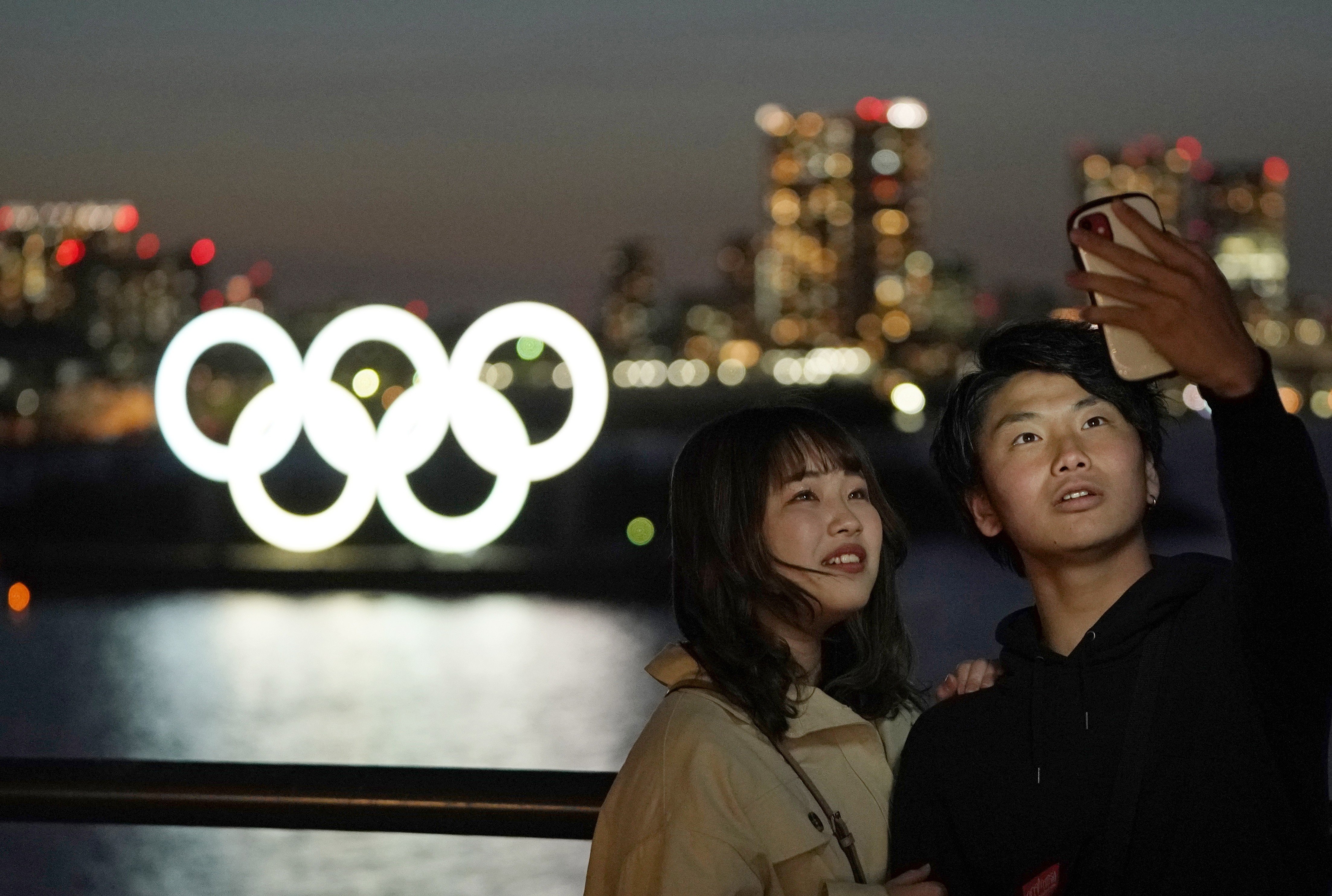 A couple take a selfie with the giant Olympic rings monument in the background at Odaiba Marine Park in Tokyo. Photo: EPA