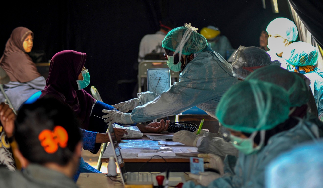 Petugas kesehatan memeriksa orang-orang yang memiliki gejala Covid-19 di Bandung, Jawa Barat.  Foto: AFP