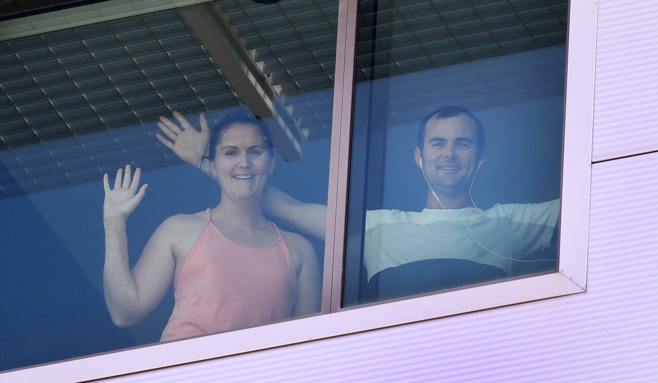 Returning overseas passengers are seen through their hotel room window while in quarantine in Brisbane. Photo: AAP