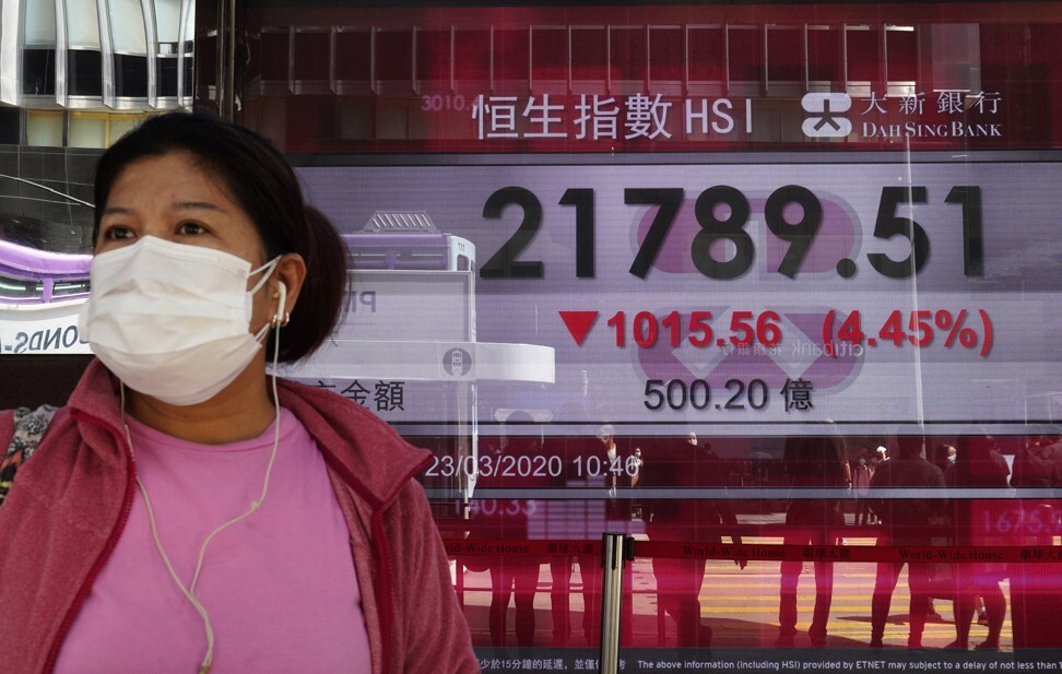 A woman wearing face mask walks past a bank electronic board showing the Hong Kong share index at Hong Kong stock exchange on March 23, 2020. Photo: AP